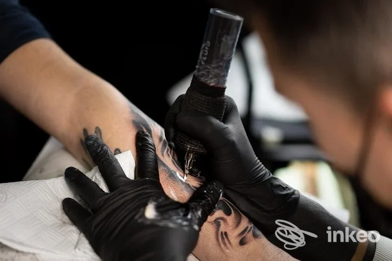 Tatuaggio in corso sull'avambraccio ripreso nello studio All Ink Tatoo ad Alessandria, dettaglio del lavoro e delle mani del tatuatore.