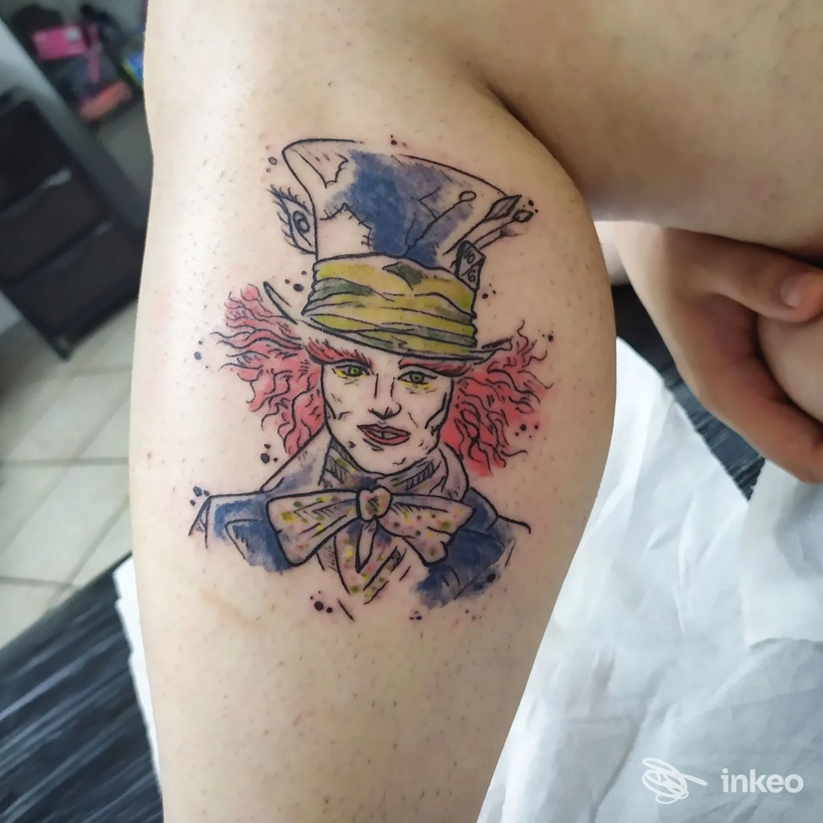 Tatuaggio su interno bicipite raffigurante un personaggio con cappello e fiocco, Arcana Cabana Ink, Imperia.