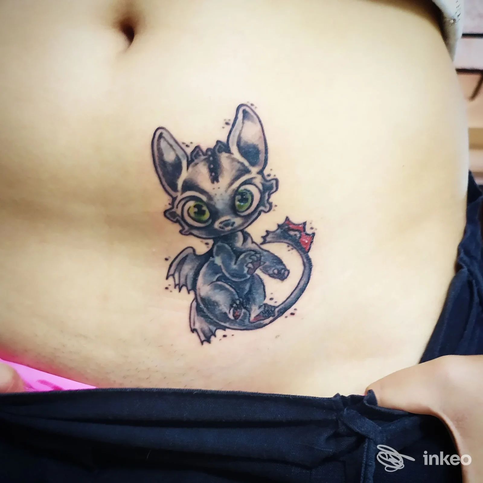 Tatuaggio di piccolo drago cartoonesco sull'addome, realizzato da Arcana Cabana Ink a Imperia.