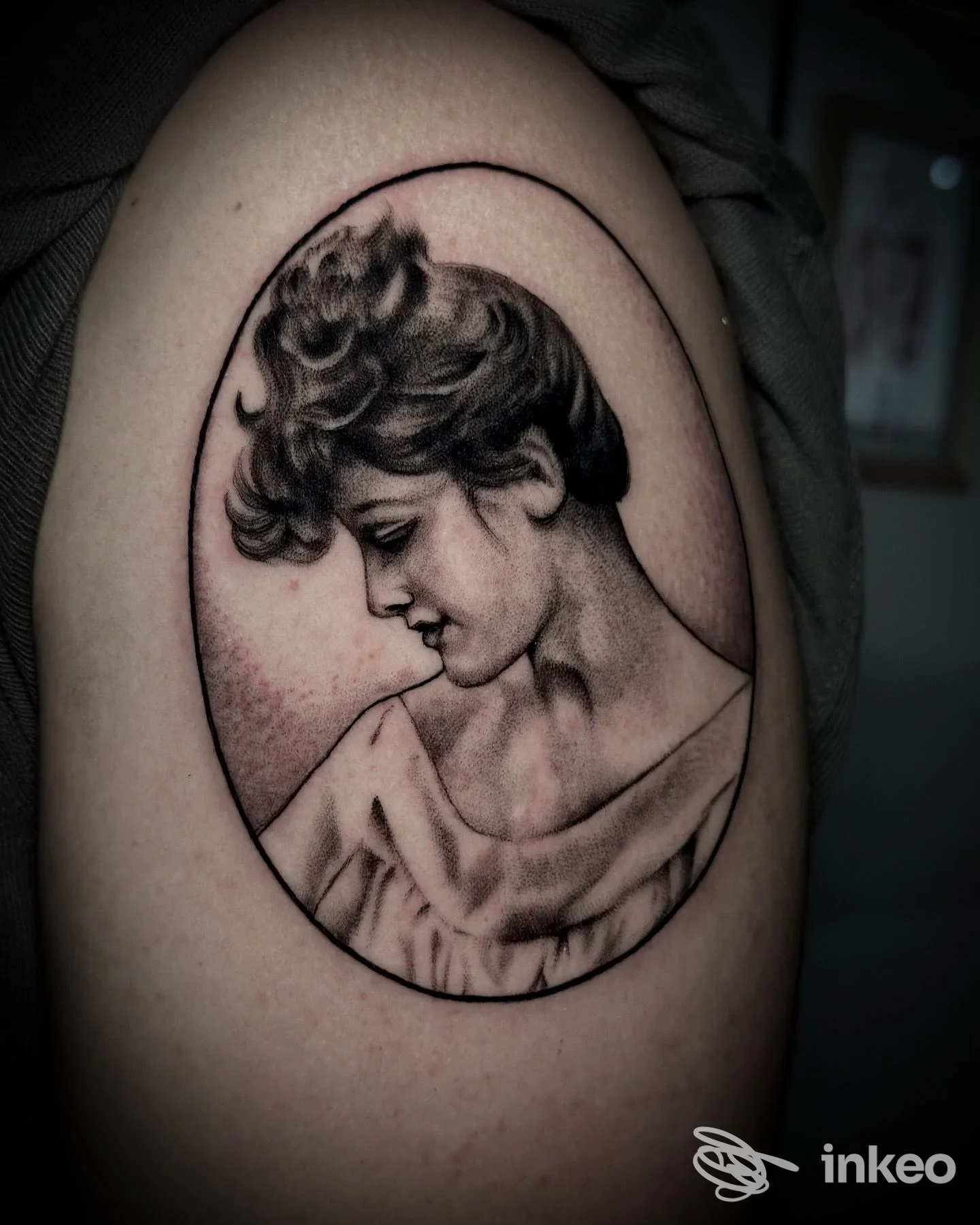 Tatuaggio realistico a mezzo busto di donna in ovale sul braccio superiore, lavoro di Melted Moon Tattoos a Gravina in Puglia.