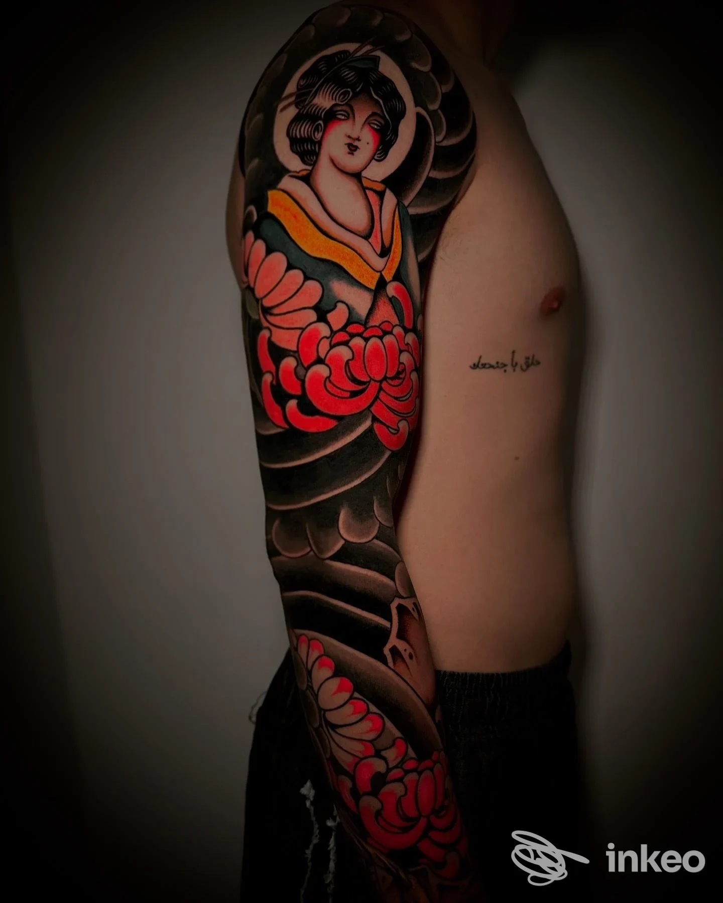 Manica completa colorata su braccio maschile esposta da Melted Moon Tattoos, Gravina in Puglia, con grandi fiori rossi e ampie ombreggiature nere.