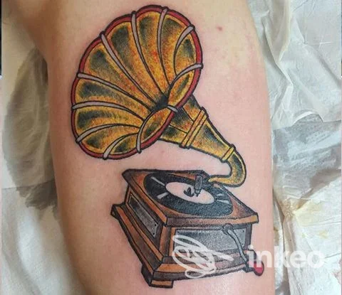 Tatuaggio sul braccio raffigurante un grammofono d'epoca, realizzazione corporea visibile su pelle.