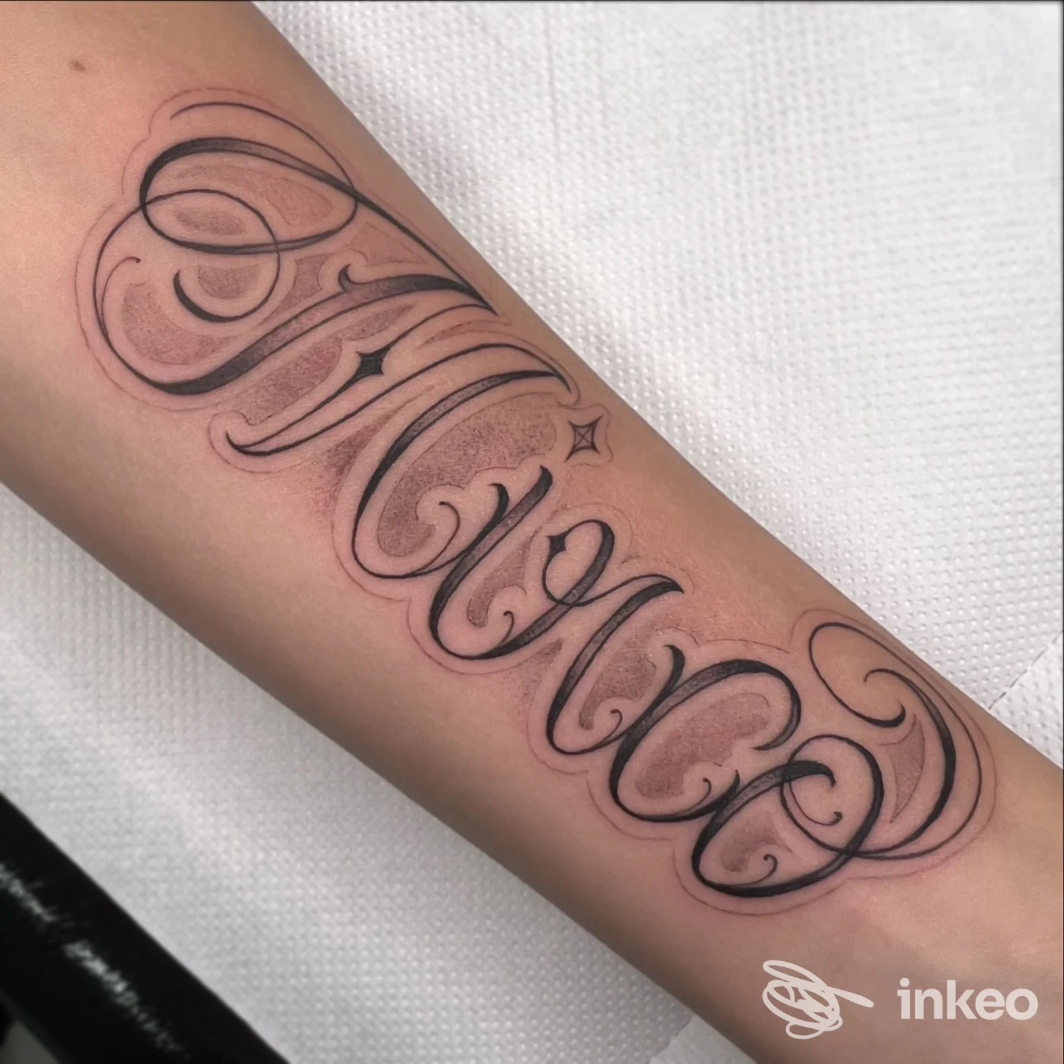 Tatuaggio lettering nero e sfumato sull'avambraccio, fotografato da Meltinpot tattoo studio a Castiglione del Lago.