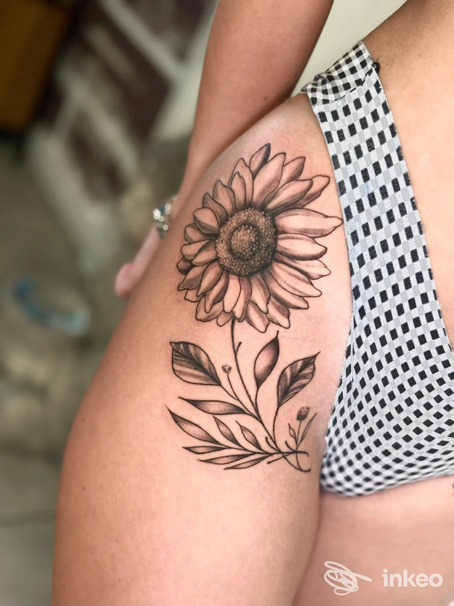 Tatuaggio girasole in bianco e nero sul fianco/coscia, fotografia del lavoro di CAOS TATTOO a Verona.