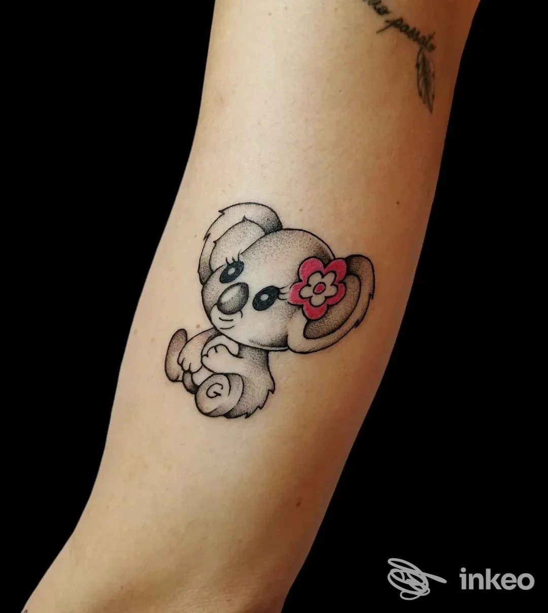 Tattoo su avambraccio di un orsetto panda con fiore rosa all'orecchio, realizzato sul corpo umano, studio Zkk-ink.