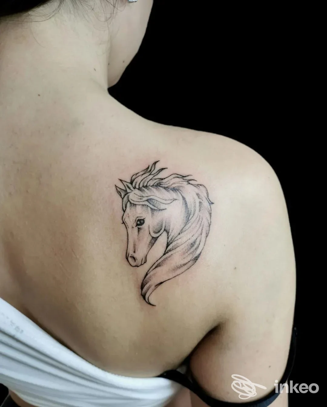 Tatuaggio su pelle raffigurante una testa di cavallo, eseguito sulla spalla della persona, linea sottile e nera.