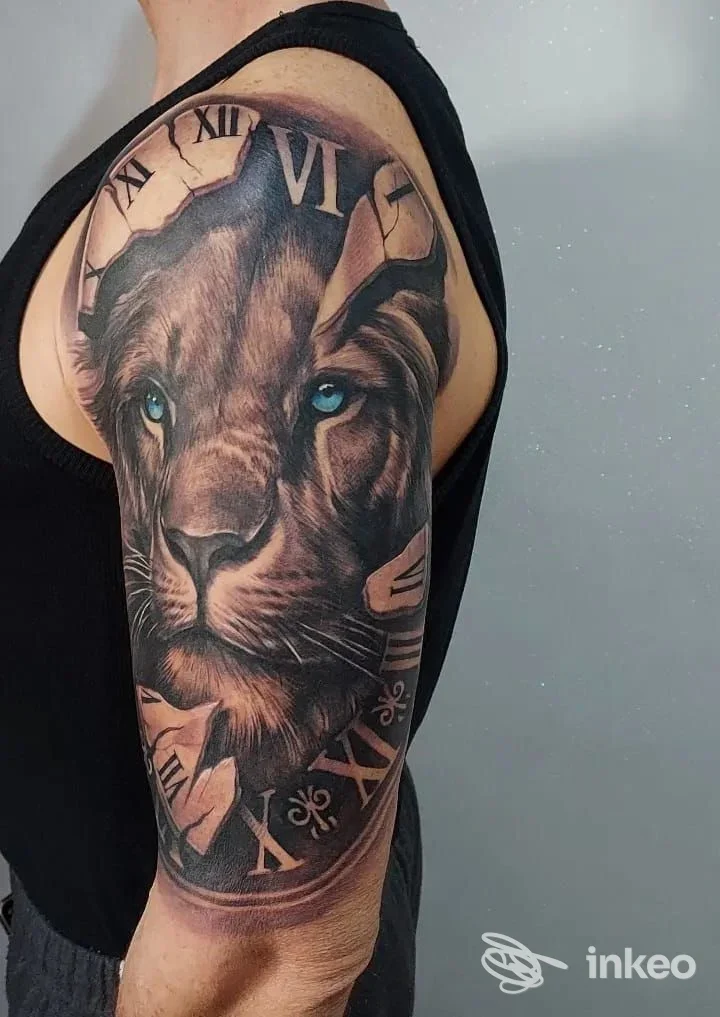 Tatuaggio realistico di un leone con occhi azzurri su braccio e spalla, fotografia per Art under Skin Tattoo studio, Prato.