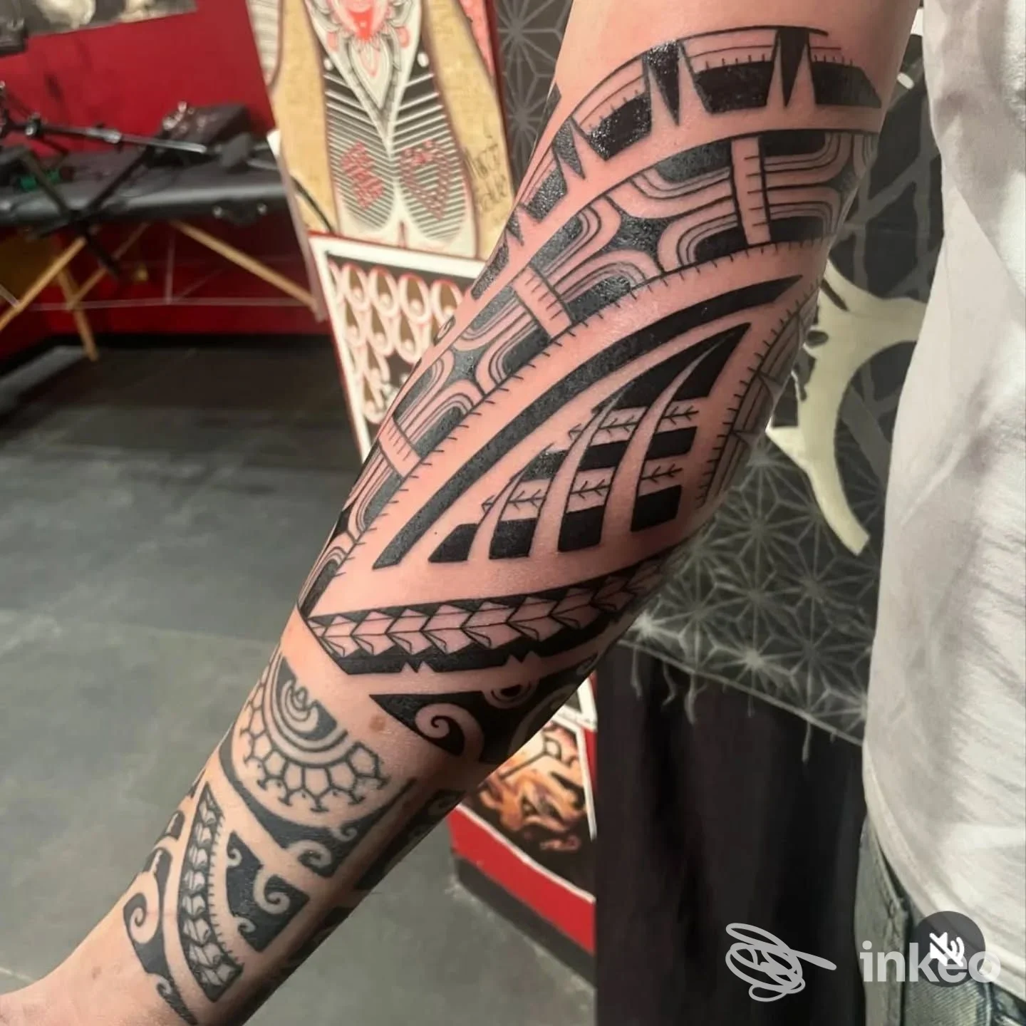 Avambraccio nudo con tatuaggio geometrico nero, motivi curvi e linee spesse, eseguito sulla pelle reale, senza volto visibile.