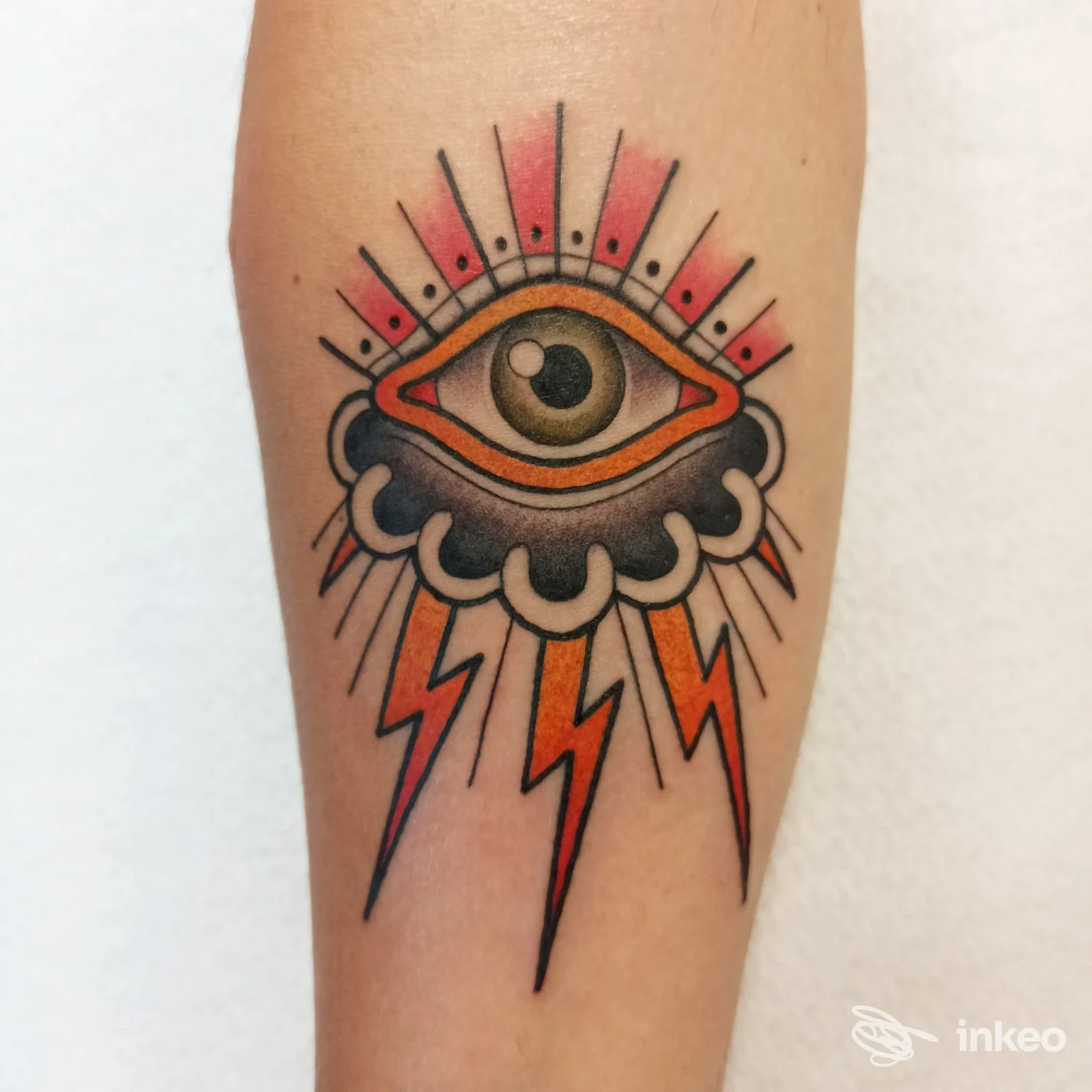 Tatuaggio su avambraccio con occhio stilizzato, nuvola e fulmini, realizzato da Inkwave Tattoo Lazise a Lazise.