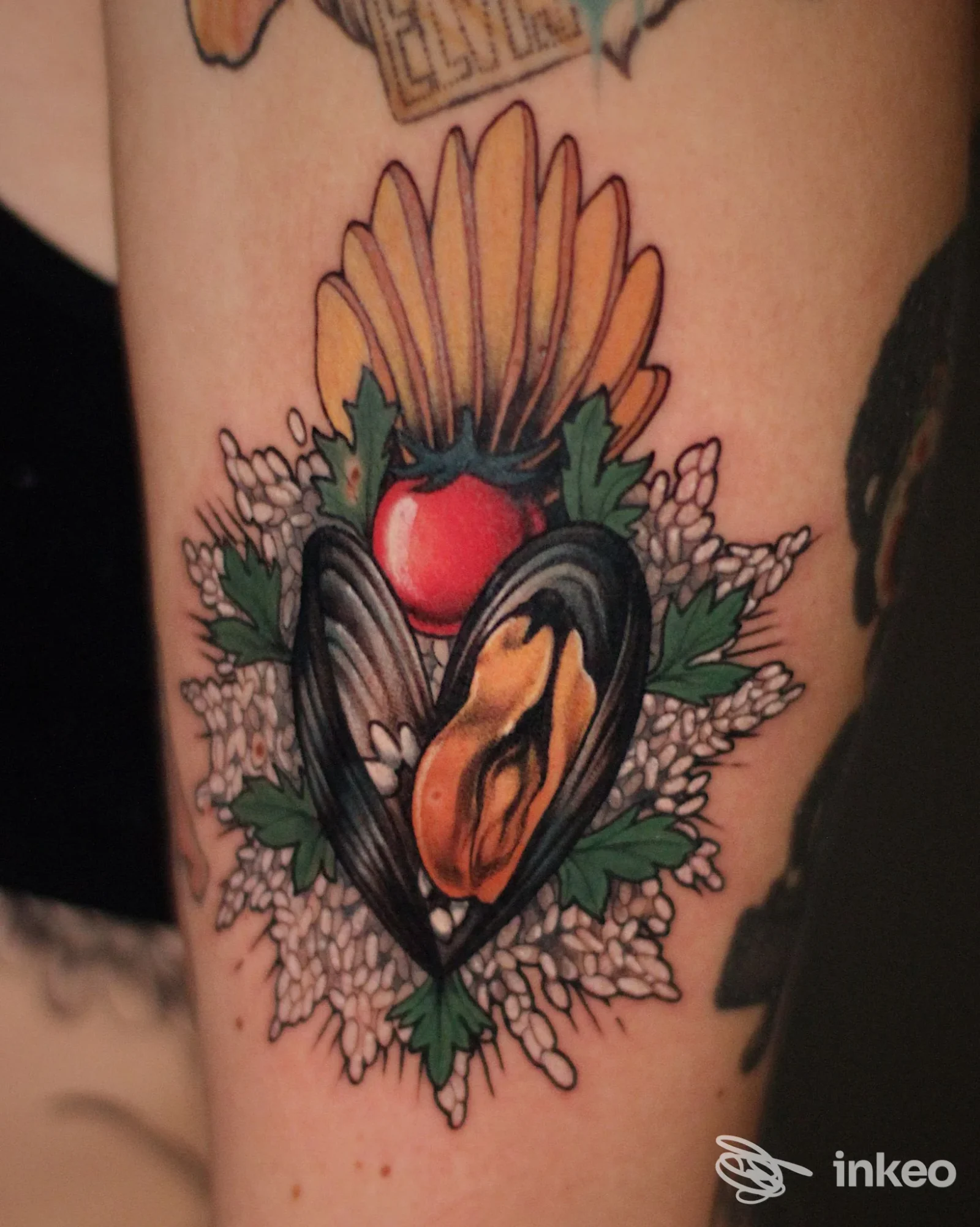 Tatuaggio colorato sul braccio superiore, fotografia fornita da Floating Flame Tattoo Gallery a Trani, soggetto con conchiglia a cuore e fiori.