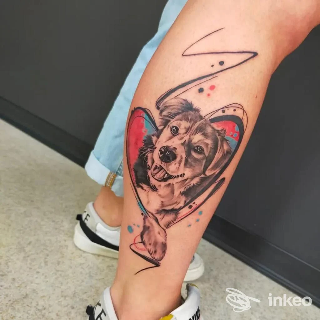 Tatuaggio su polpaccio: ritratto realistico di un cane dentro un cuore con accenti colorati, lavoro di Psyco22tattoo a Badia Polesine.