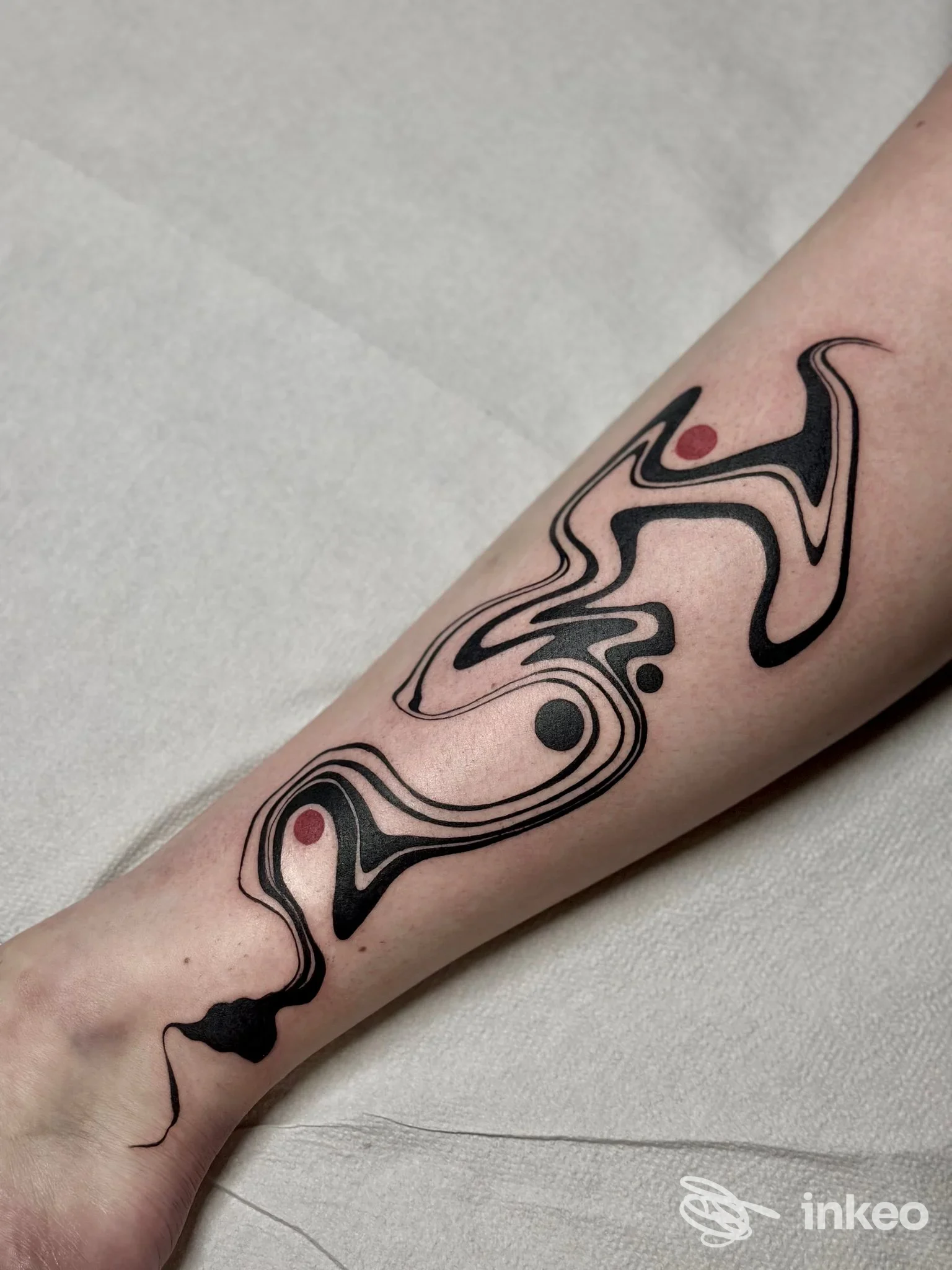 Tatuaggio astratto in nero e rosso su avambraccio, Downtown Ink Verona, Verona.