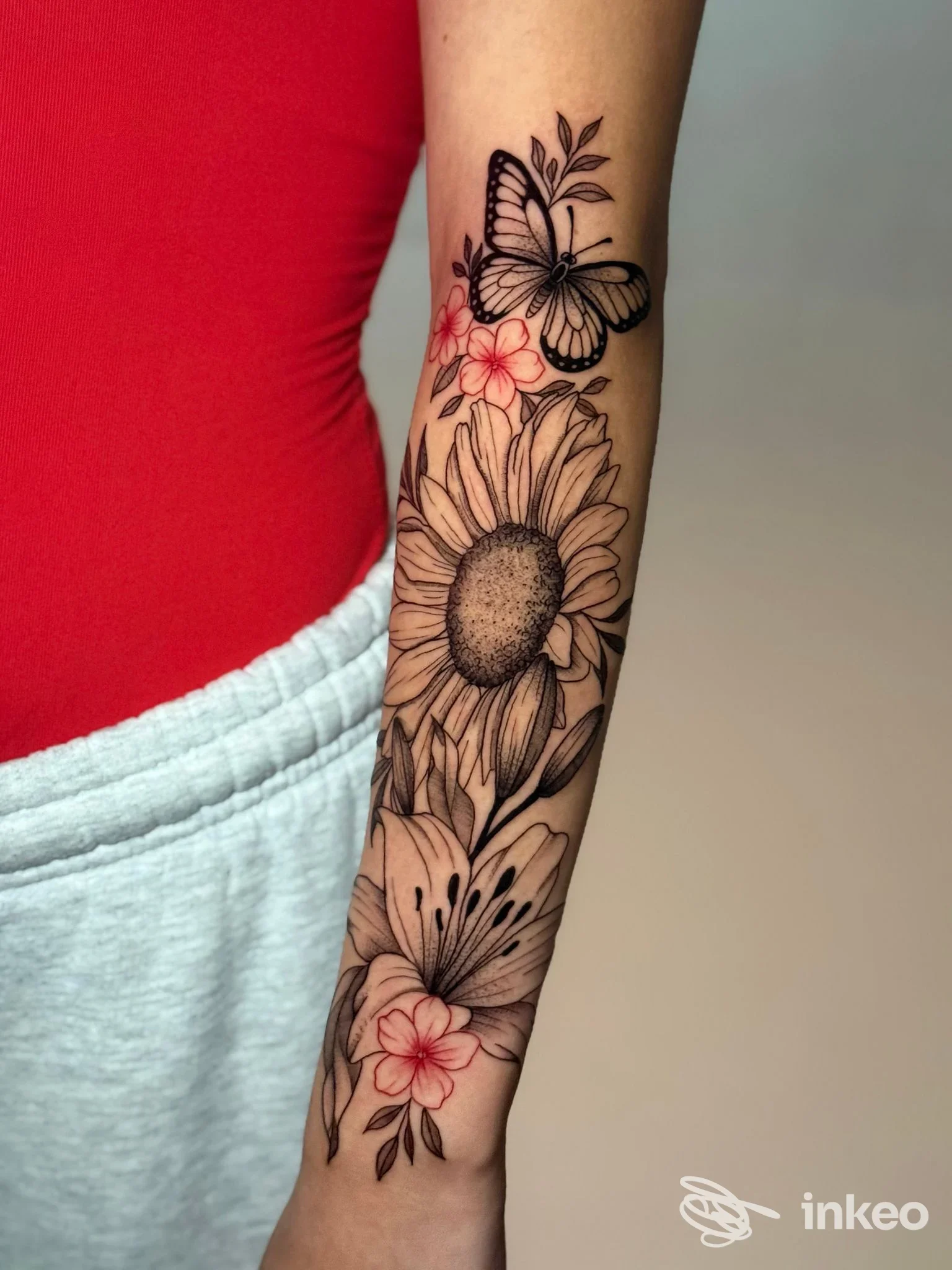 Tatuaggio floreale sull'avambraccio con girasole, giglio e farfalla, foto inviata dallo studio Downtown Ink Verona.
