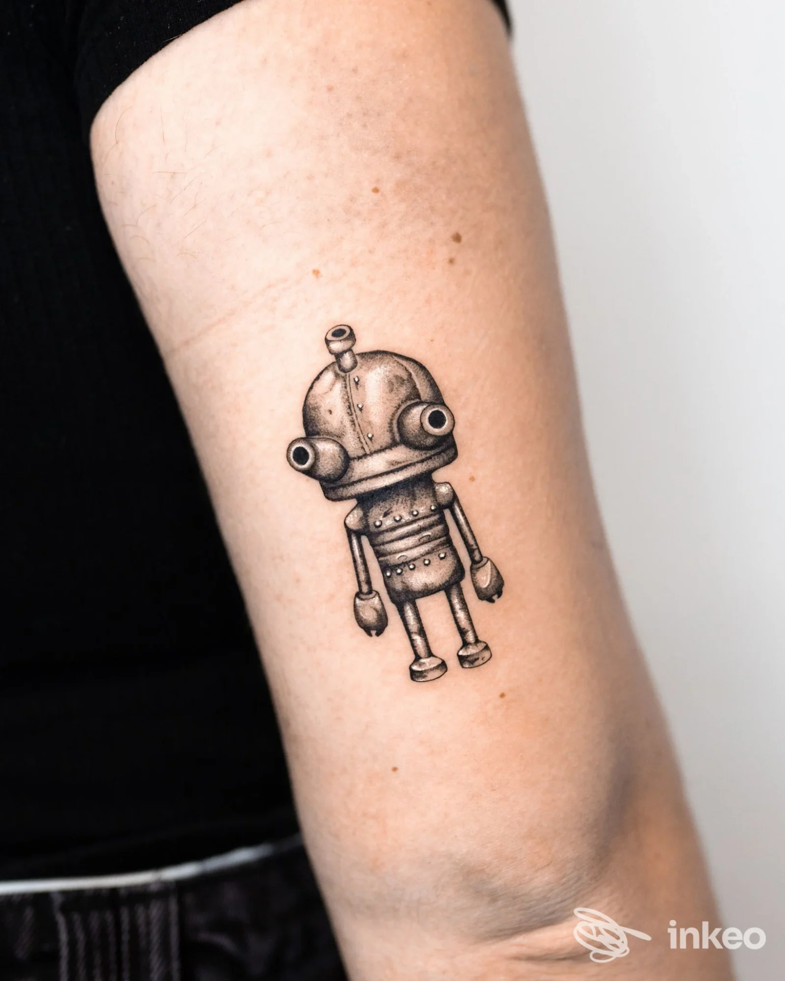 Tatuaggio robot stilizzato in bianco e nero sul braccio superiore, foto fornita da Happy Ink Parlor, Merano.