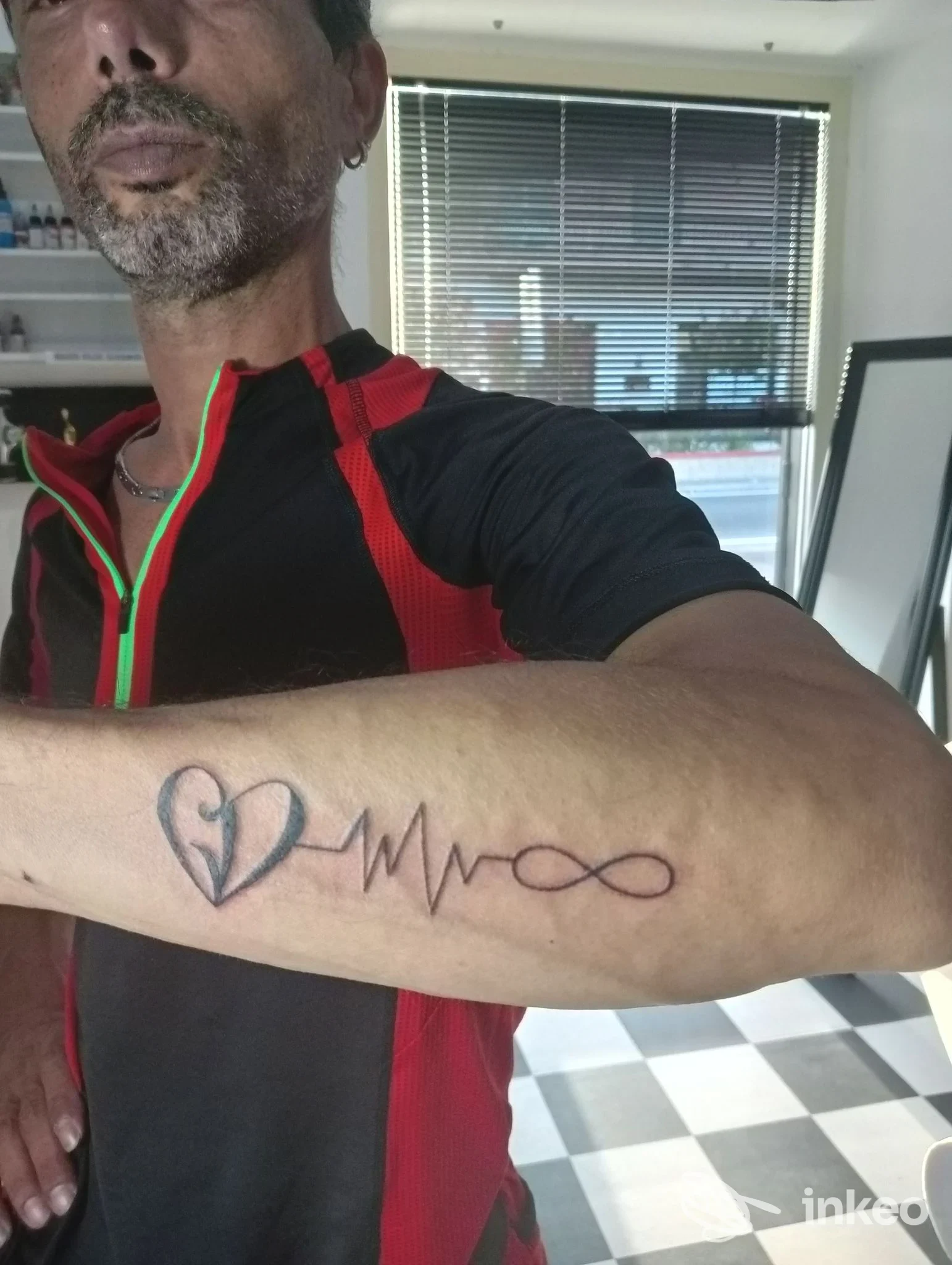 Primo piano di avambraccio tatuato con cuore, linea cardiaca e simbolo dell'infinito, foto dallo studio Spartaco Tattoo a Frosinone.