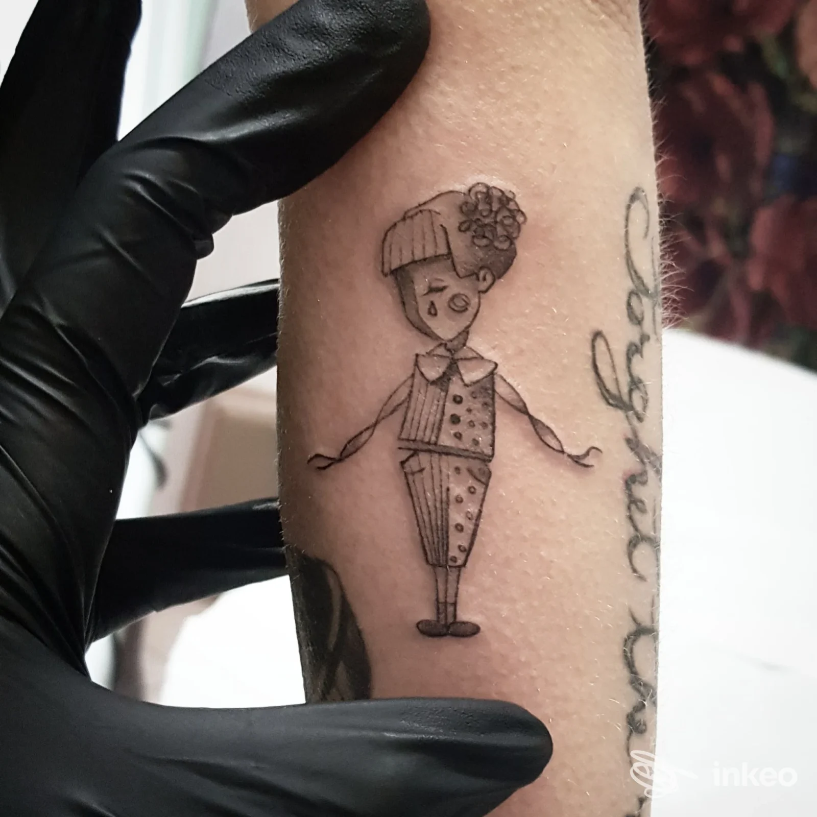 Tatuaggio linework di una bambola stilizzata sull'avambraccio, foto fornita da Grammofono Tattoo Vetralla, Vetralla.