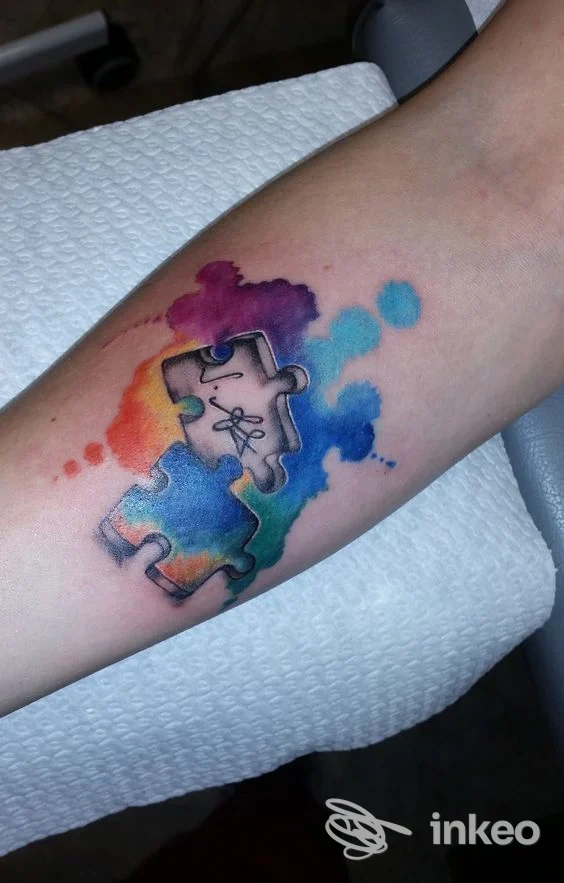 Tatuaggio acquerello a pezzi di puzzle sull'avambraccio, realizzato da Ink&Ele a Ghislarengo.