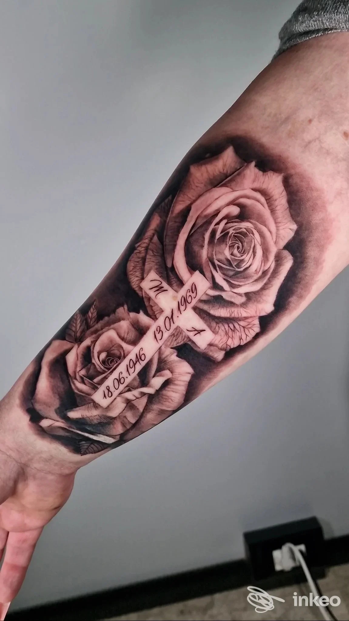 Tatuaggio realistico di due rose con nastro e date sull'avambraccio, foto fornita da Onirico Tattoo studio a Rieti.