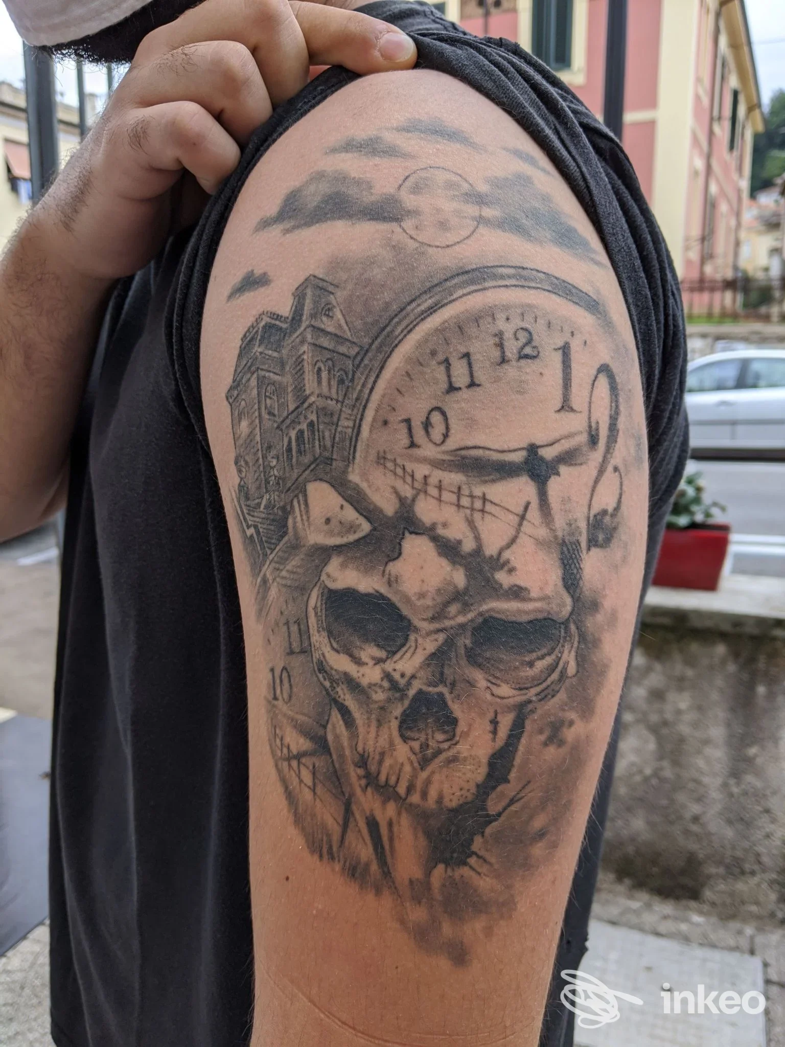Tatuaggio black & grey sul bicipite con teschio, orologio e edificio, foto del lavoro eseguito da Danjotattoo a Isola del Liri.