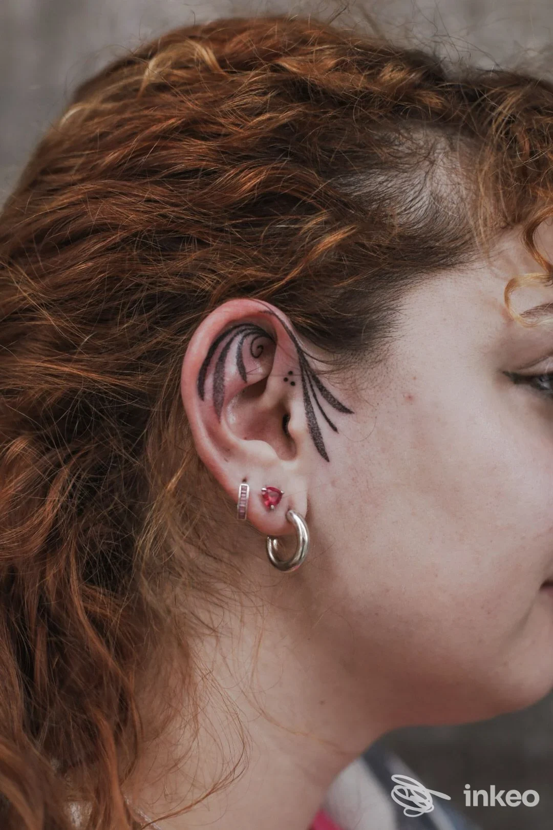 Dettaglio di un piccolo tatuaggio a linee dietro l'orecchio su una persona con piercing, Distort Tattoo House, Tortona.