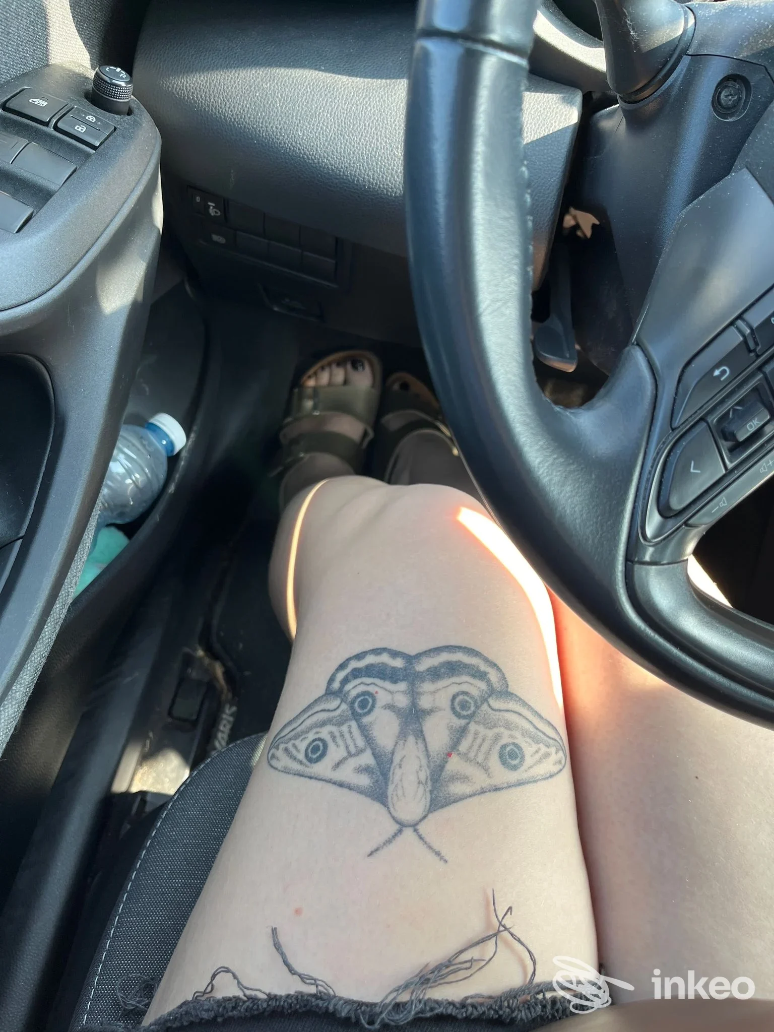 Gamba seduta in auto con tatuaggio a forma di falena sulla coscia, foto inviata da Distort Tattoo House a Tortona.