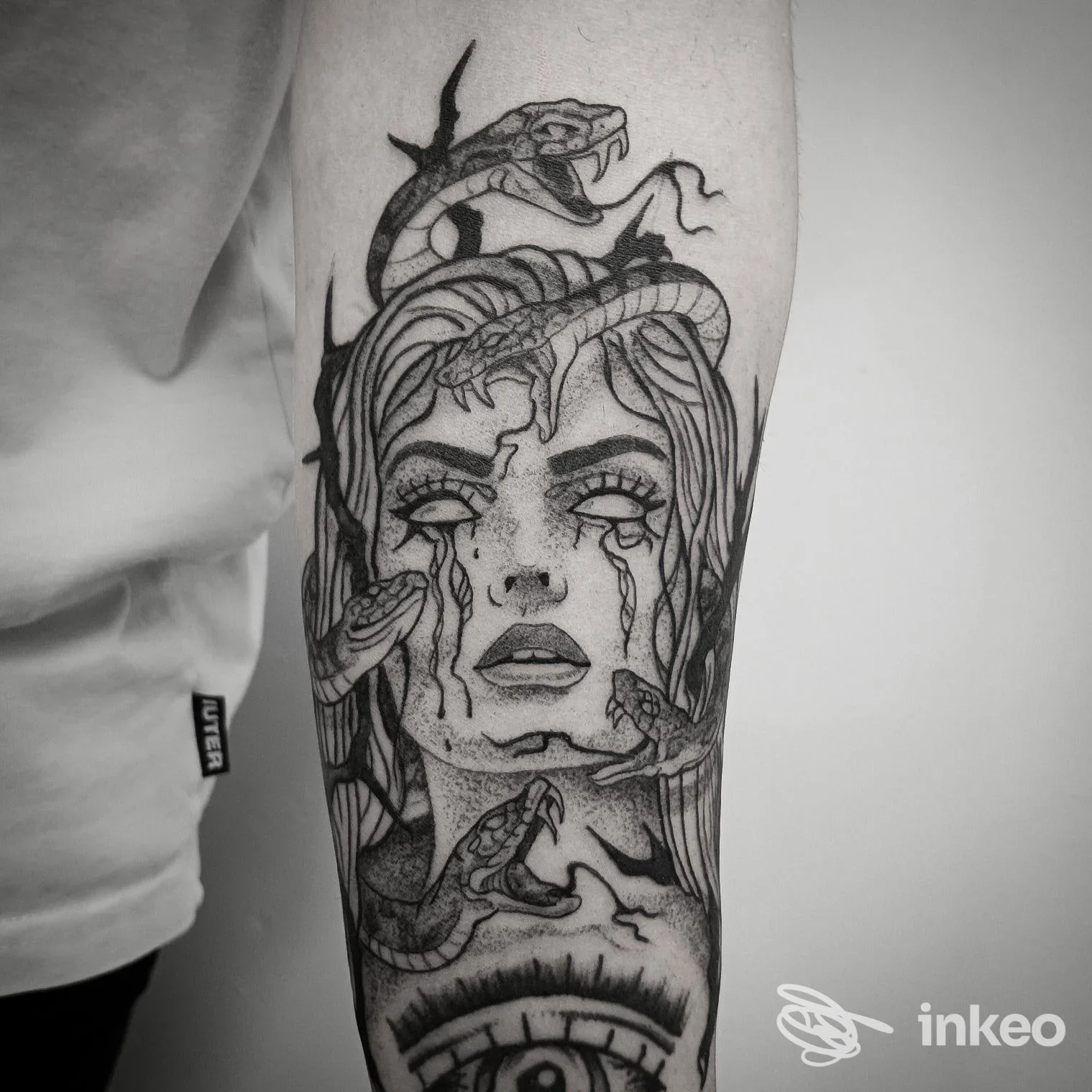 Tatuaggio realistico in bianco e nero sull'avambraccio: volto femminile stilizzato con serpenti. Animanimale Tattoo, Caerano di San Marco.