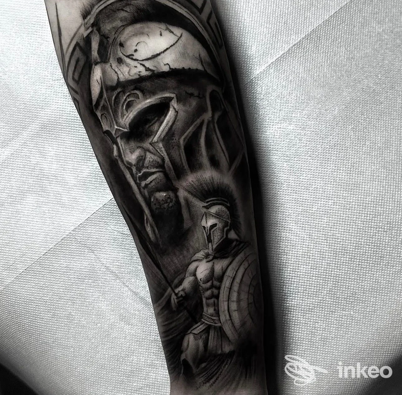 Tatuaggio realistico in bianco e nero sull'avambraccio, ritratto e figura spartana. Free Spirit Ink Matteo Spada, Decimomannu.