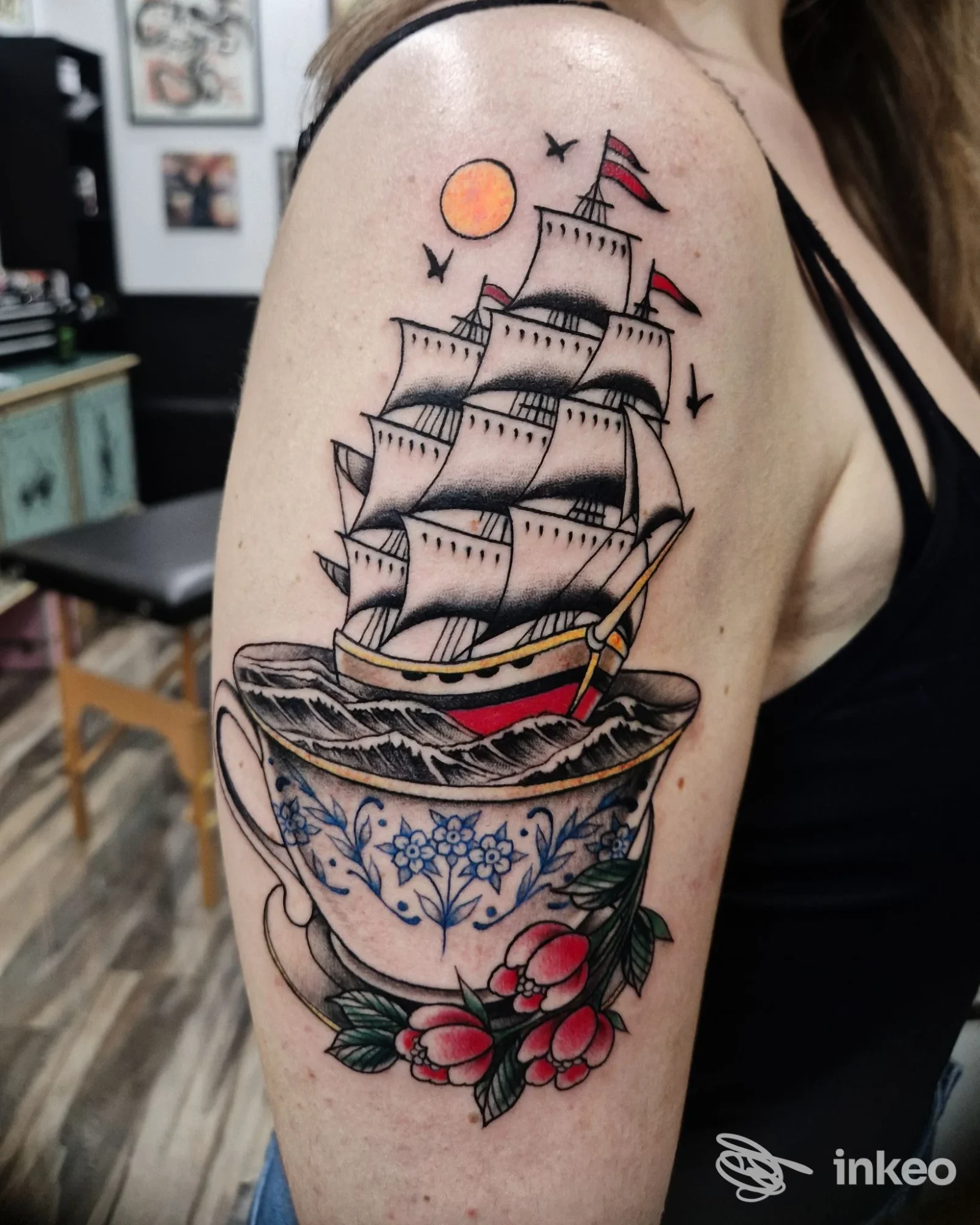 Tatuaggio colorato su spalla con nave a vele che emerge da una tazza, foto dallo studio BLACK BEAR TATTOO SHOP APRILIA, Aprilia.