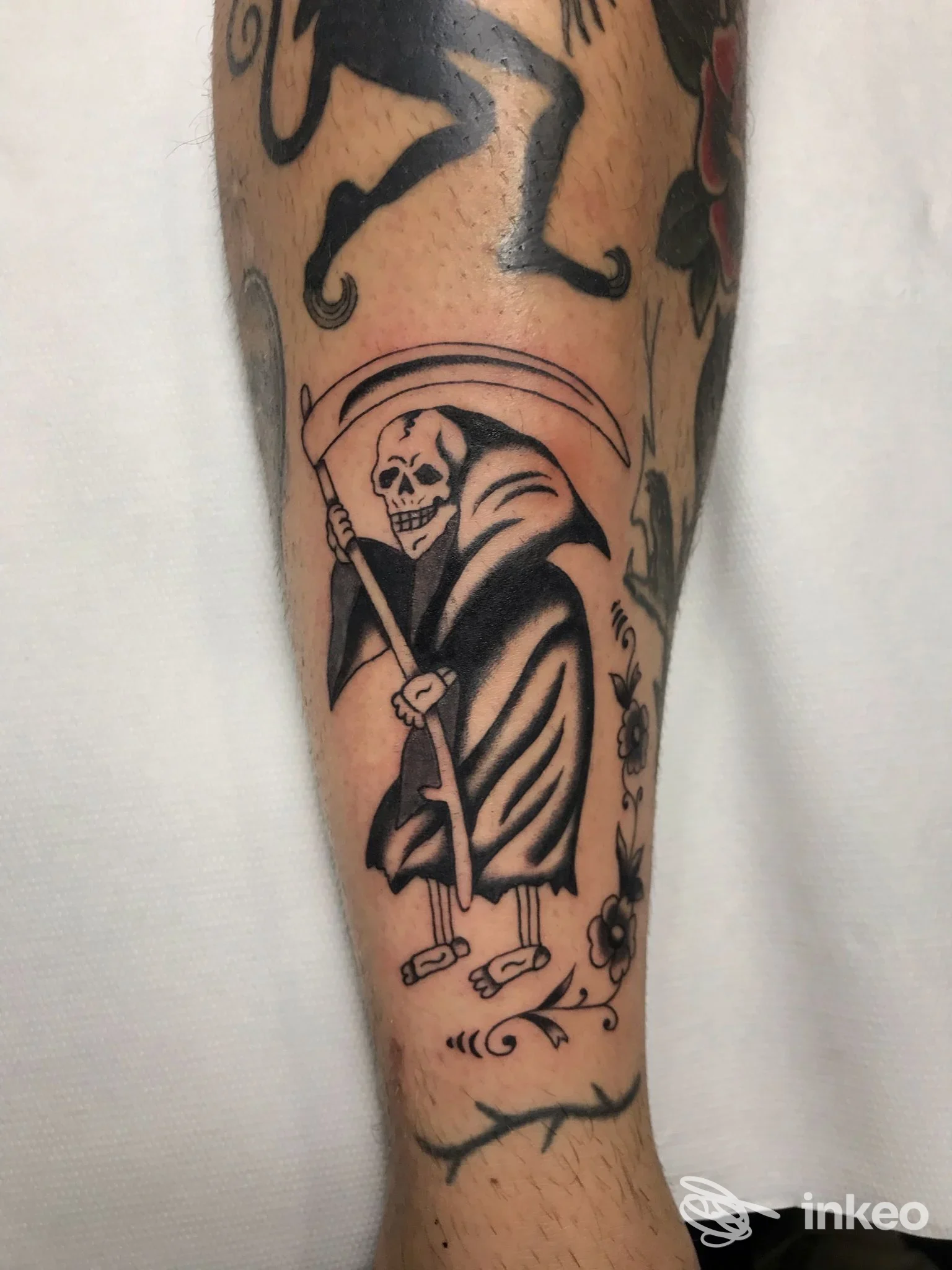 Tatuaggio tradizionale di un teschio con falce sul polpaccio, foto inviata da Ink Hustler, Genova.