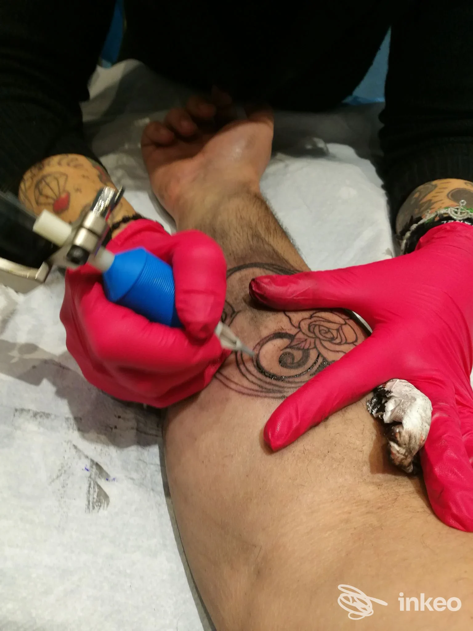 Tatuaggio in corso sull'avambraccio eseguito da Nadia Electric Tattoo a Ferrara, artista con guanti mentre riempie un motivo floreale.
