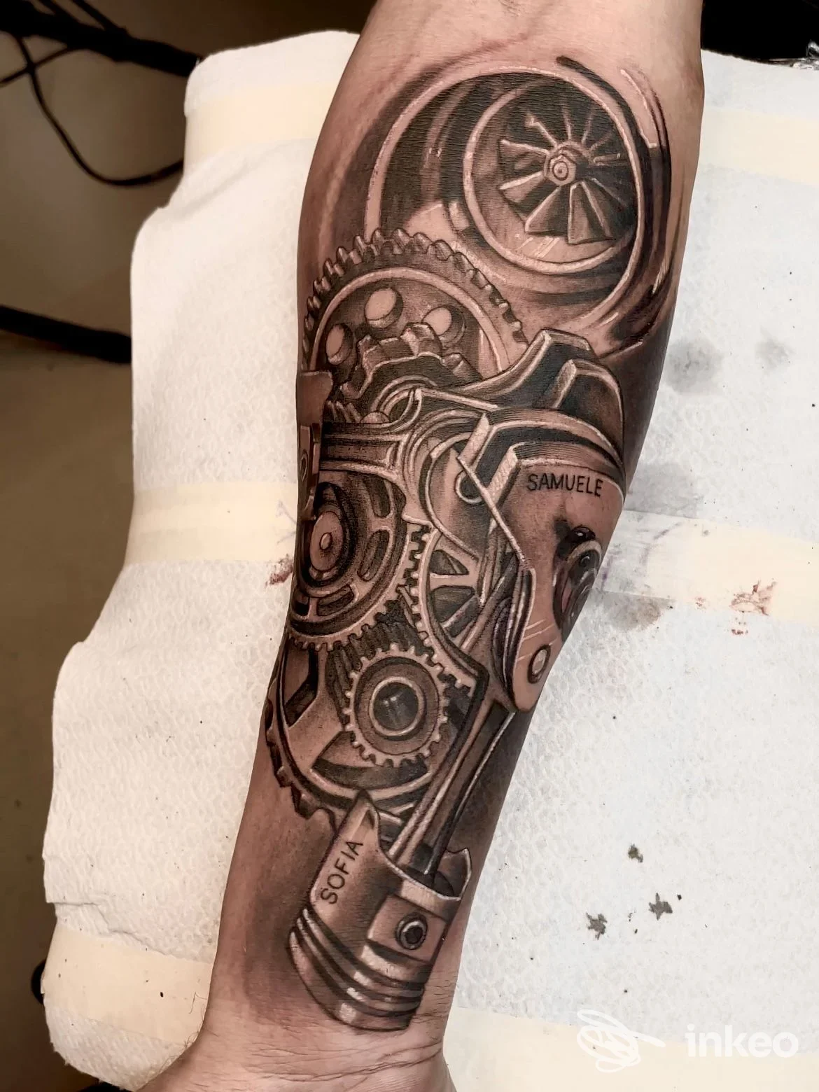 Primo piano di tatuaggio biomeccanico realistico sull'avambraccio con ingranaggi e pistone, lavoro eseguito da Kiù Tattoo - Luigi Sgaramella a Corato.