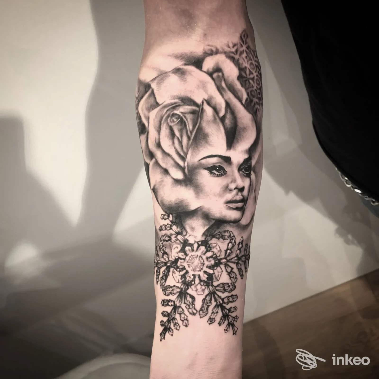 Tatuaggio in bianco e nero su avambraccio: rosa che si fonde con volto femminile e ornamenti floreali. N3 Tattoo Shop, San Bonifacio.