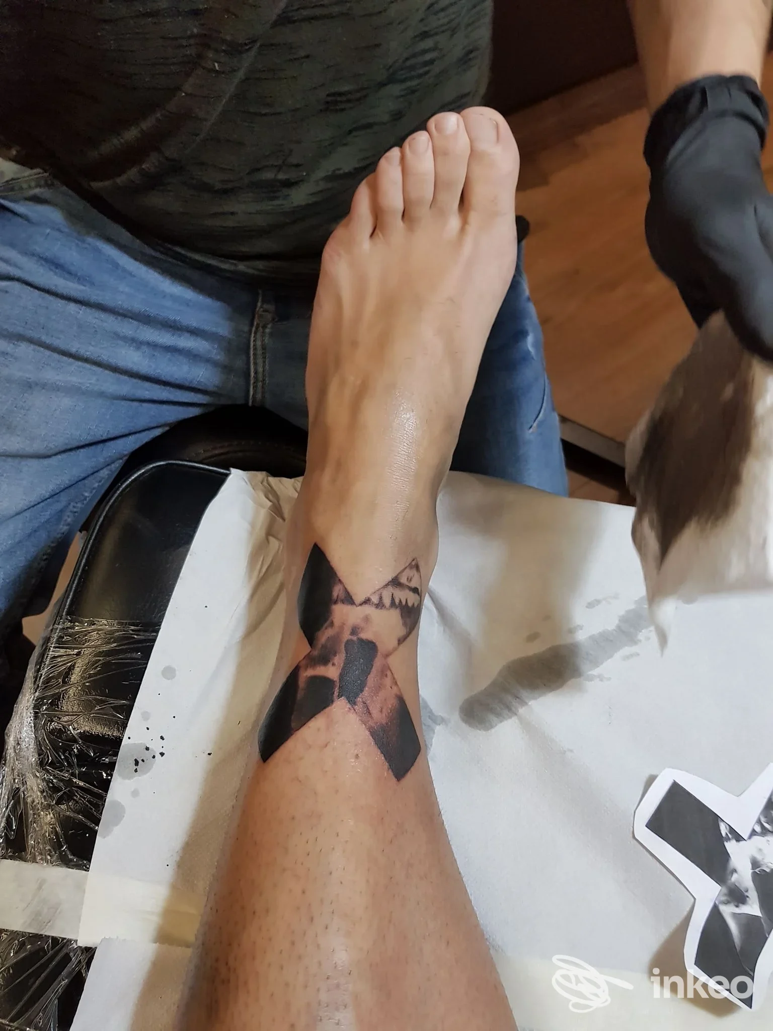 Tatuaggio nero a forma di X sulla caviglia/polpaccio, foto scattata in studio; Logan Tattoo Studio, Valenza.