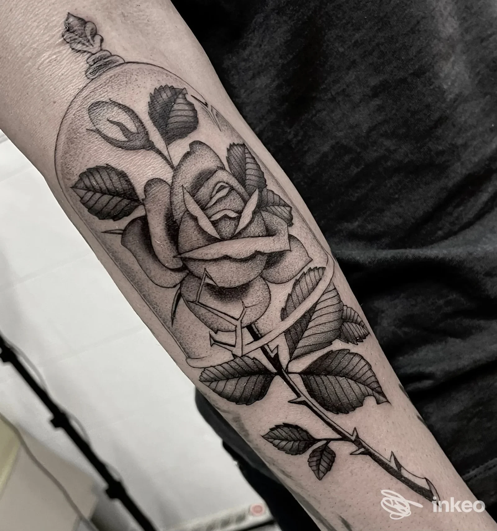 Tatuaggio nero e grigio a forma di rosa con gambo sull'avambraccio, immagine fornita da Left Hand Studio tattoo, Roma.