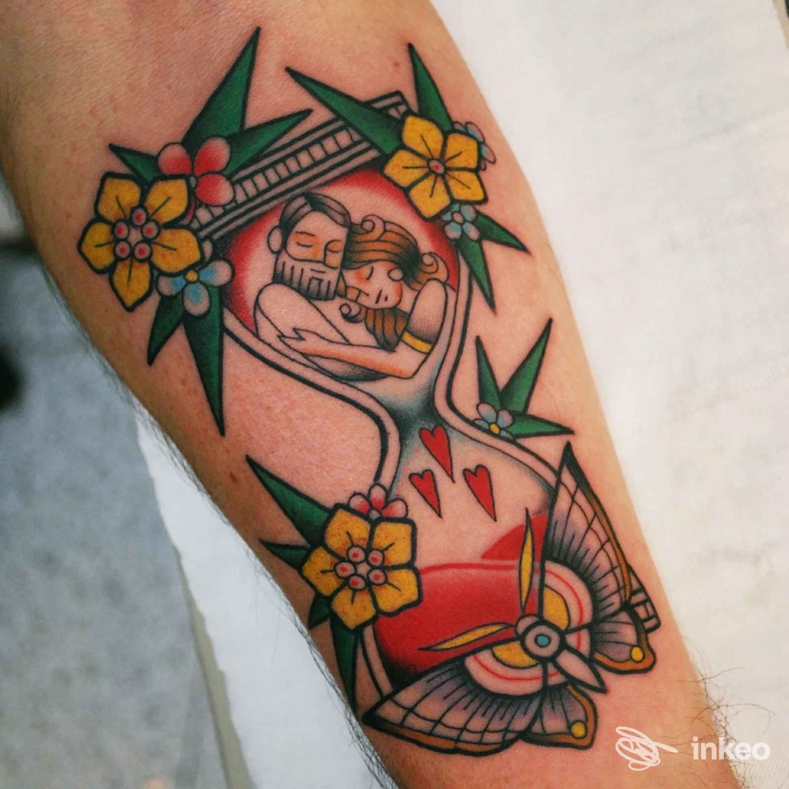 Tatuaggio colorato su avambraccio con clessidra, fiori e cuori — Left Hand Studio tattoo, Roma.