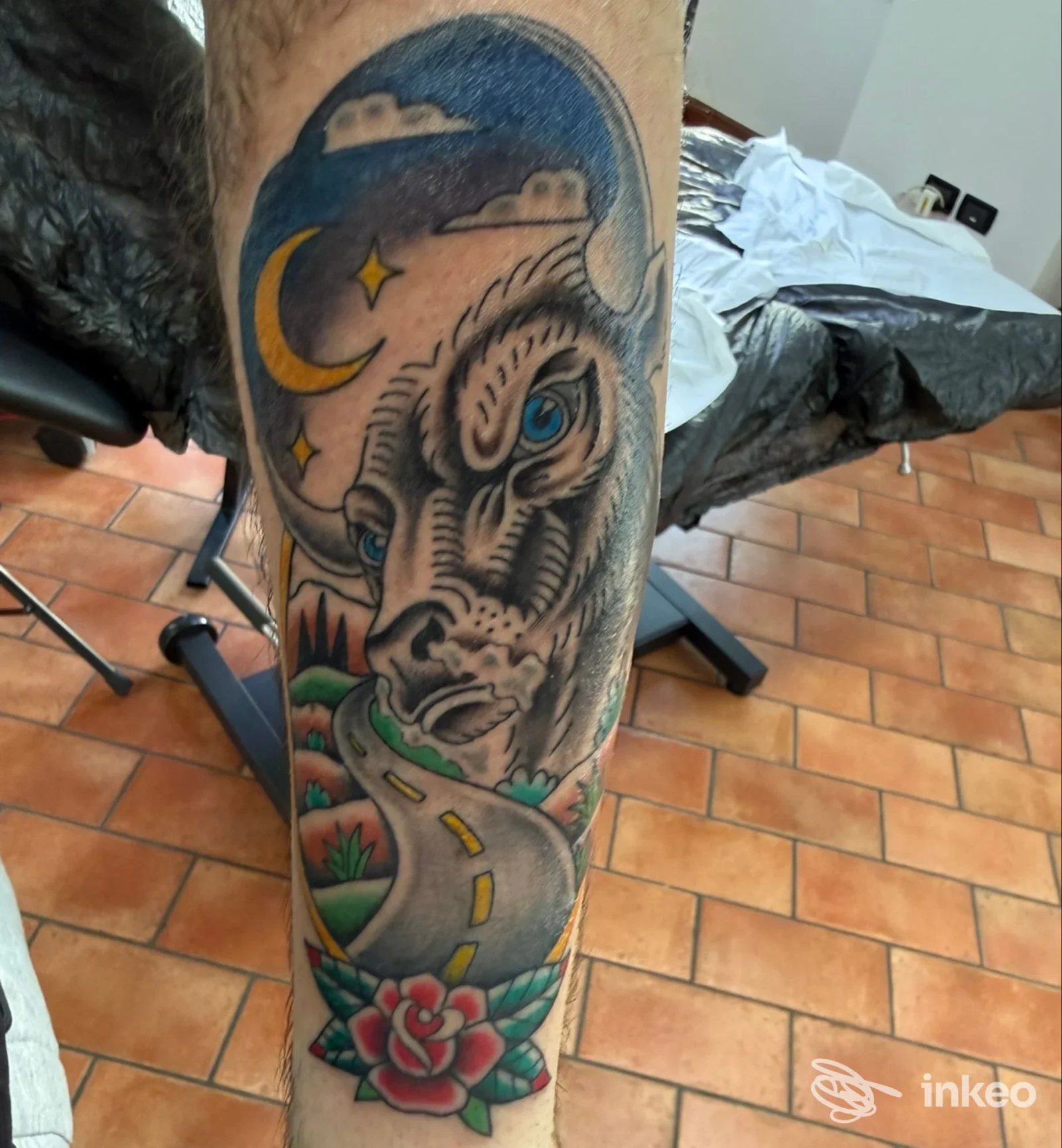 Tatuaggio su polpaccio con volto di bue, cielo notturno, strada e fiore; immagine scattata nello studio Secret Family Tattoo Studio a Sommacampagna.
