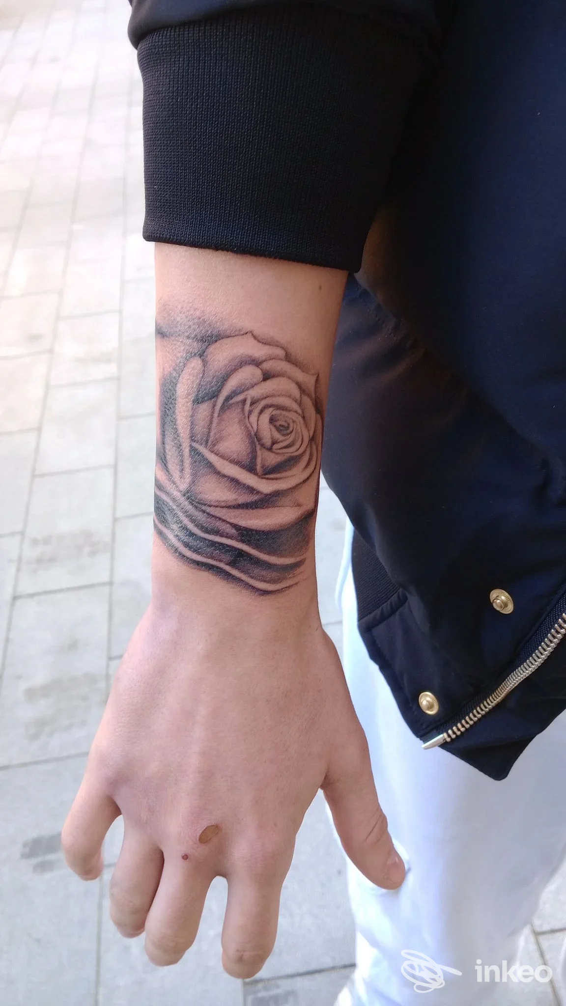 Avambraccio con tatuaggio realistico di una rosa in bianco e nero sul polso, realizzato da Psilocybink a Taggia.