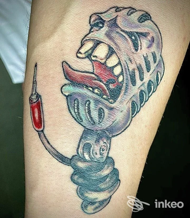 Tatuaggio colorato su avambraccio raffigurante una maschera boccheggiante collegata a una siringa, realizzato da Bad Apple Ink a Tito.