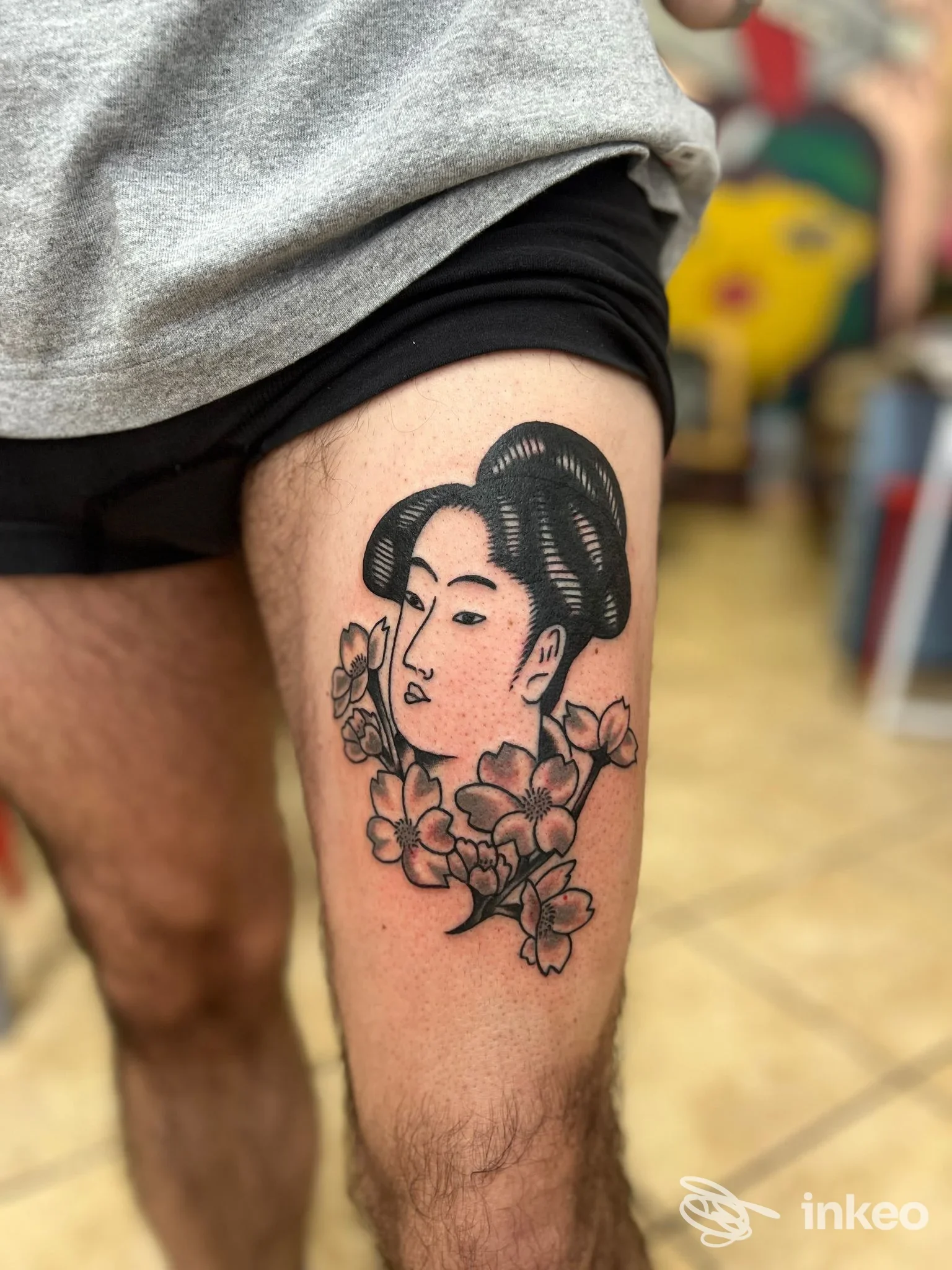 Foto di un tatuaggio stilizzato con volto femminile e fiori sulla coscia, realizzato da Studio Boreale a Cagliari.