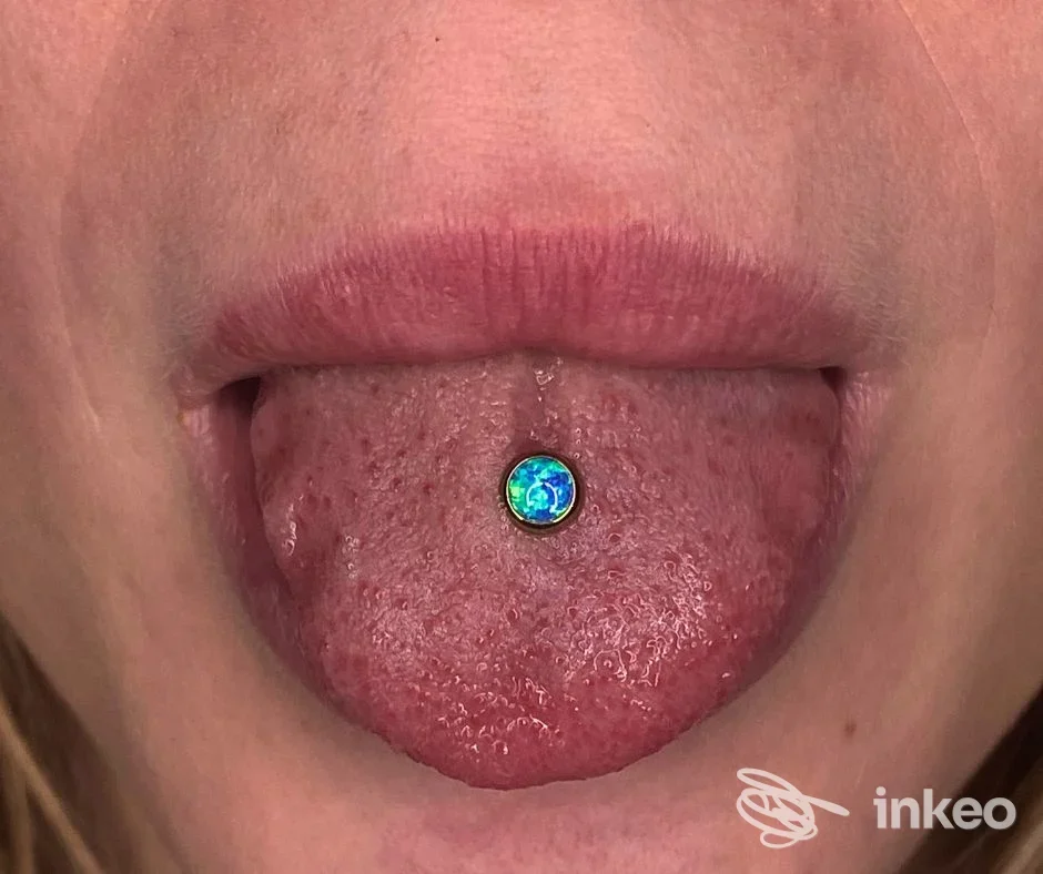 Primo piano del piercing al centro della lingua con gioiello blu-verde, foto fornita dallo studio Madame Forò a Bagheria.