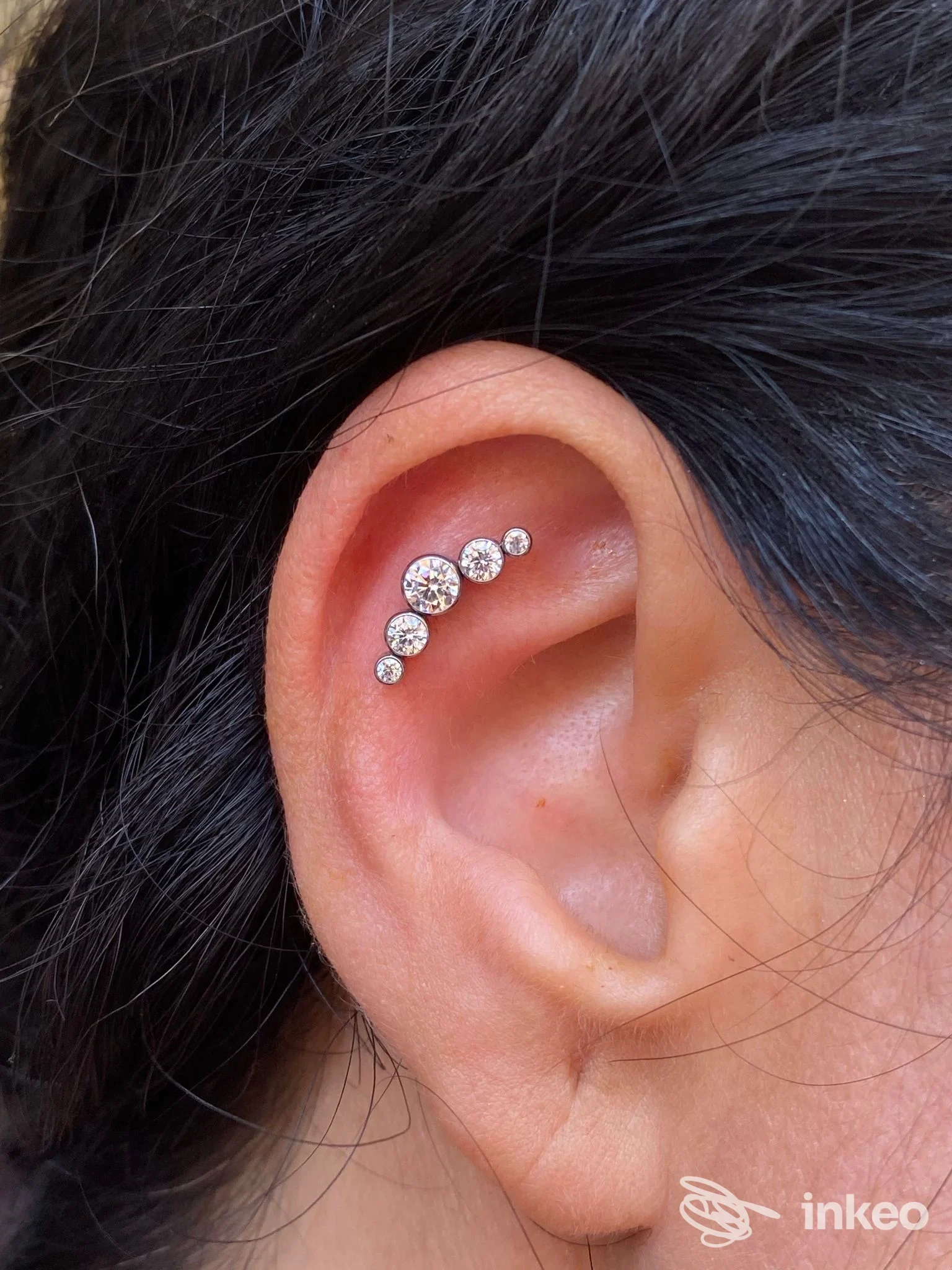 Primo piano di orecchio con cinque gioielli lungo la conca, lavoro di piercing realizzato da Madame Forò a Bagheria.