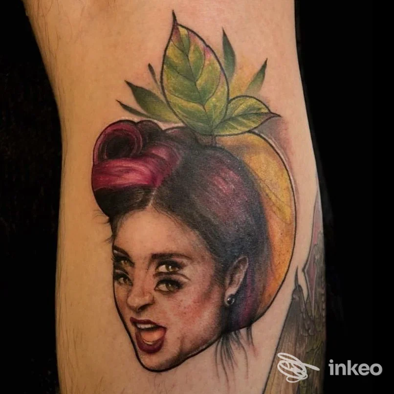 Tatuaggio colorato su avambraccio raffigurante una testa stilizzata in una pesca. Studio MUGMUGMUG, Venezia.