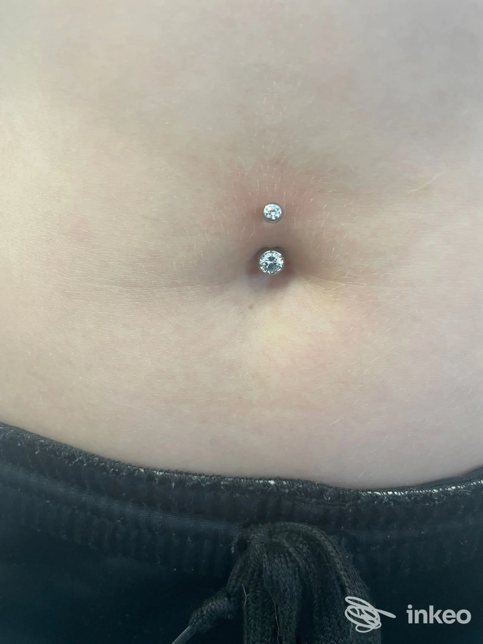 Primo piano di un piercing ombelicale con gioielli lucenti su pelle naturale, eseguito da Studio 55 Vicenza a Vicenza.
