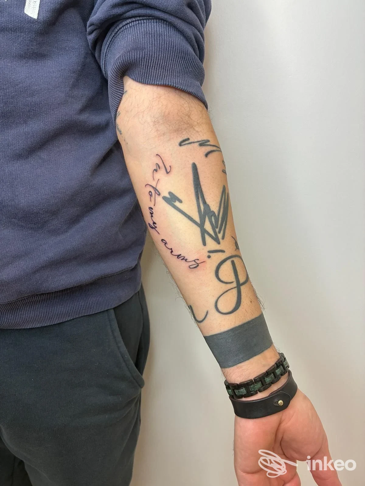 Avambraccio con vari tatuaggi neri, inclusa una banda al polso e scritte in corsivo — ANICHINI MARTINA, Poggibonsi.