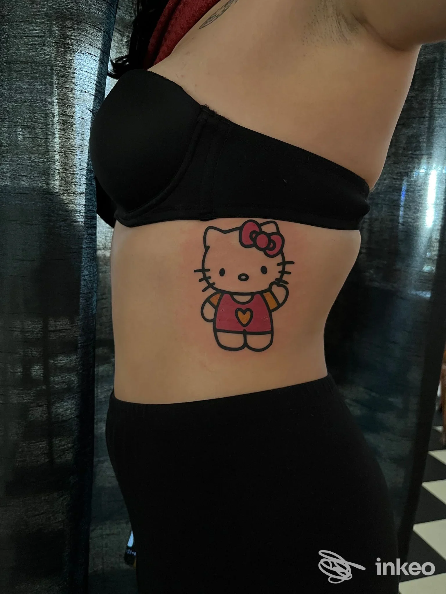 Tatuaggio Hello Kitty colorato sul fianco di una persona, realizzato da OTHERSIDE artigiano dell'inchiostro a Hône.