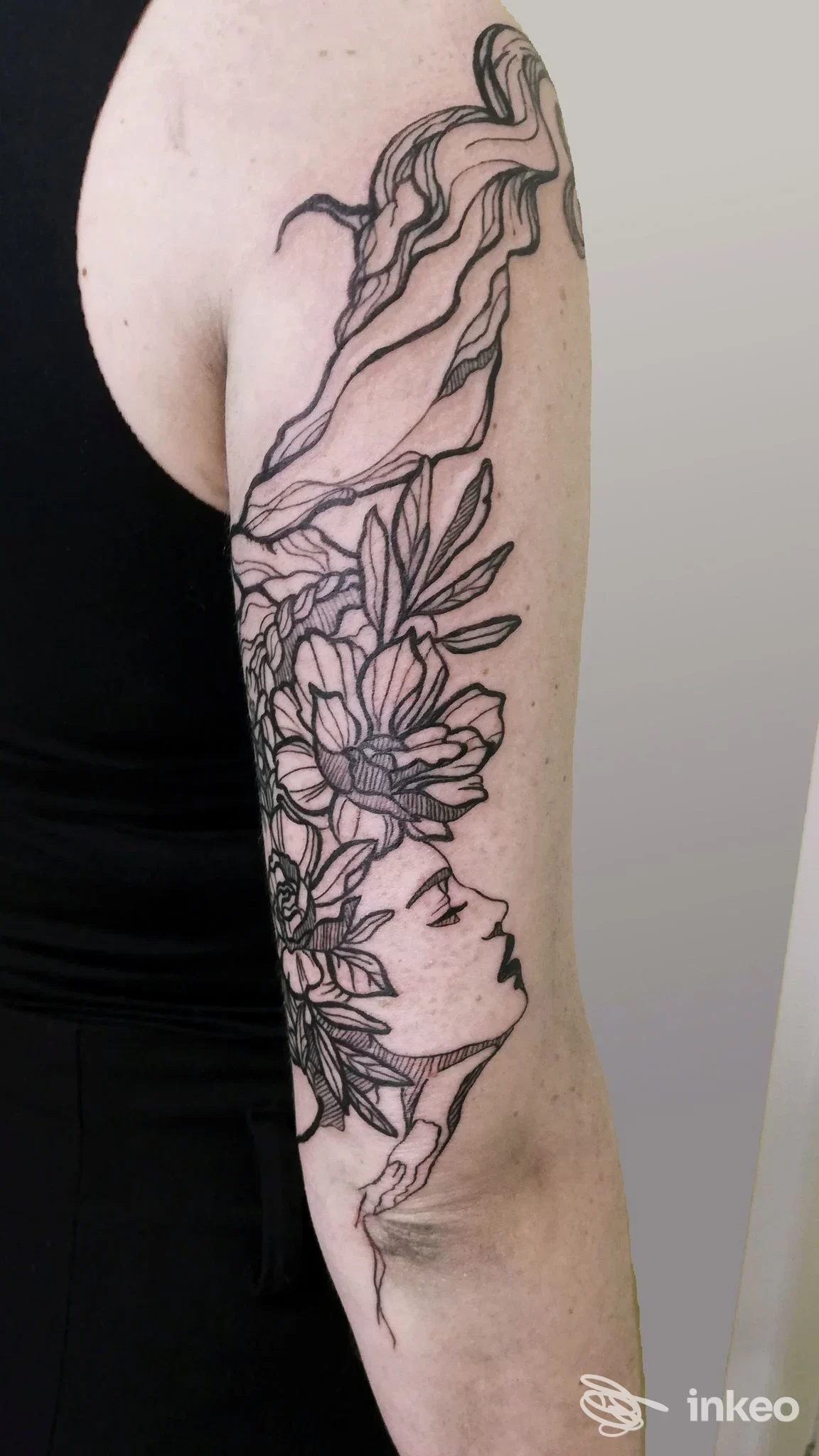 Tatuaggio a linee nere con fiori e profilo stilizzato sul braccio, Petalo Nero Tattoo Atelier, Conegliano.