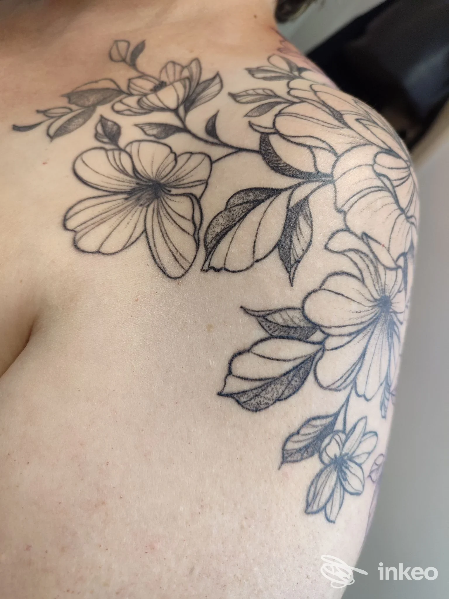 Grande tatuaggio floreale nero su spalla e petto, con linee e ombreggiature delicate. Immagine per portfolio di Petalo Nero Tattoo Atelier, Conegliano.