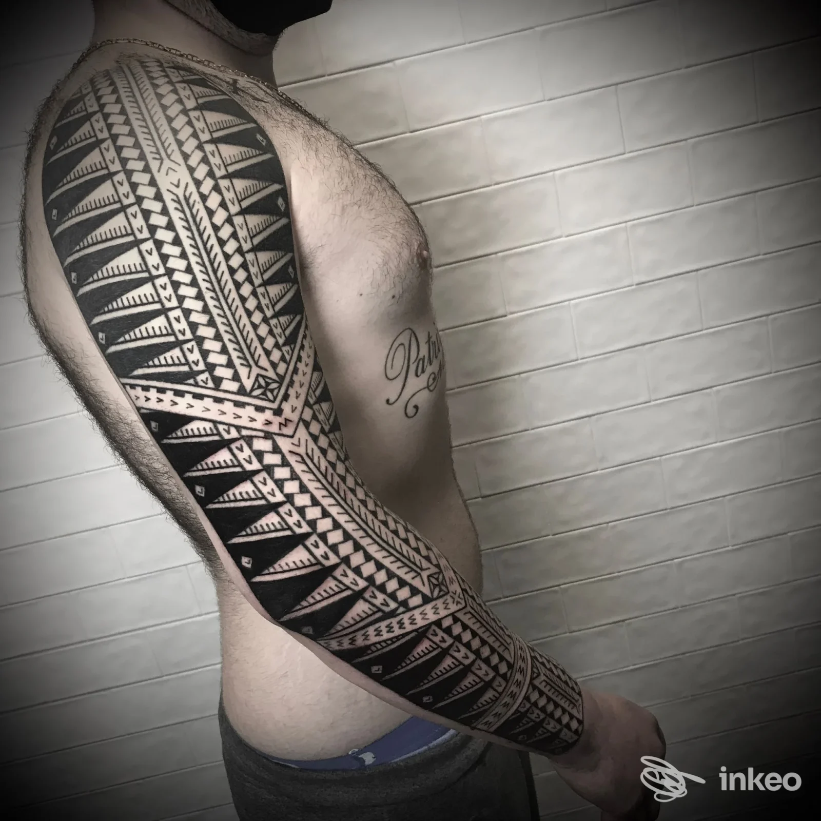 Tatuaggio a manica tribale/polinesiano sul braccio destro e fianco di un uomo, foto per Raniero Patutiki a Genova.