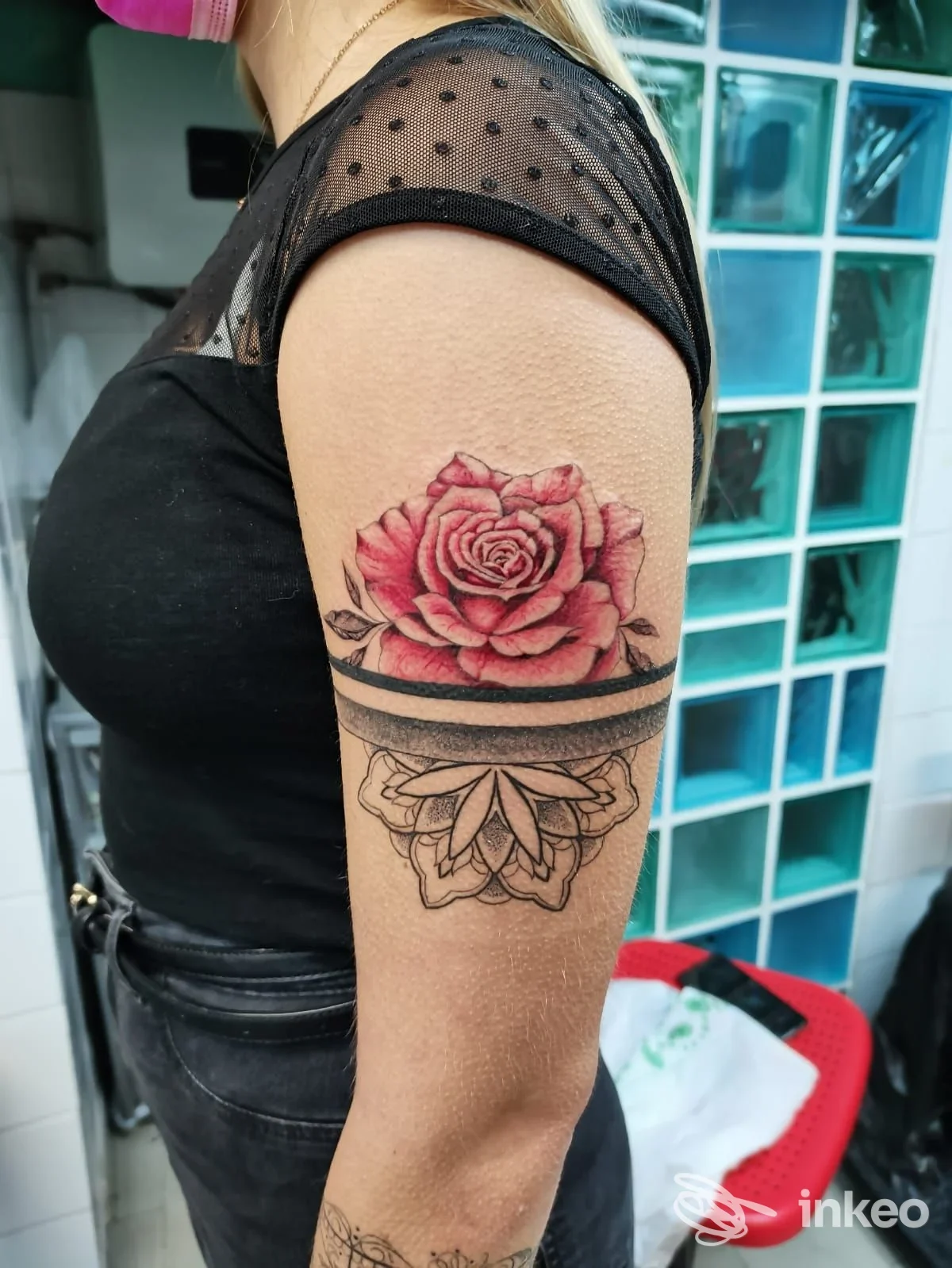 Tatuaggio di una rosa colorata con decorazione ornamentale sul bicipite di una cliente, foto realizzata da Sacred Art a Varazze.