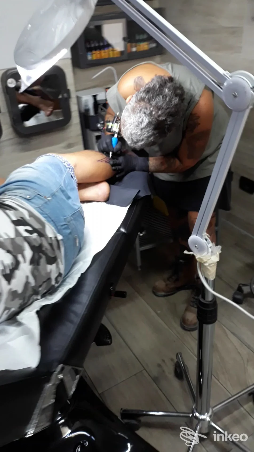 Tatuatore al lavoro sulla gamba di un cliente nello studio Il Bunker Delle Torture a Grottaglie.